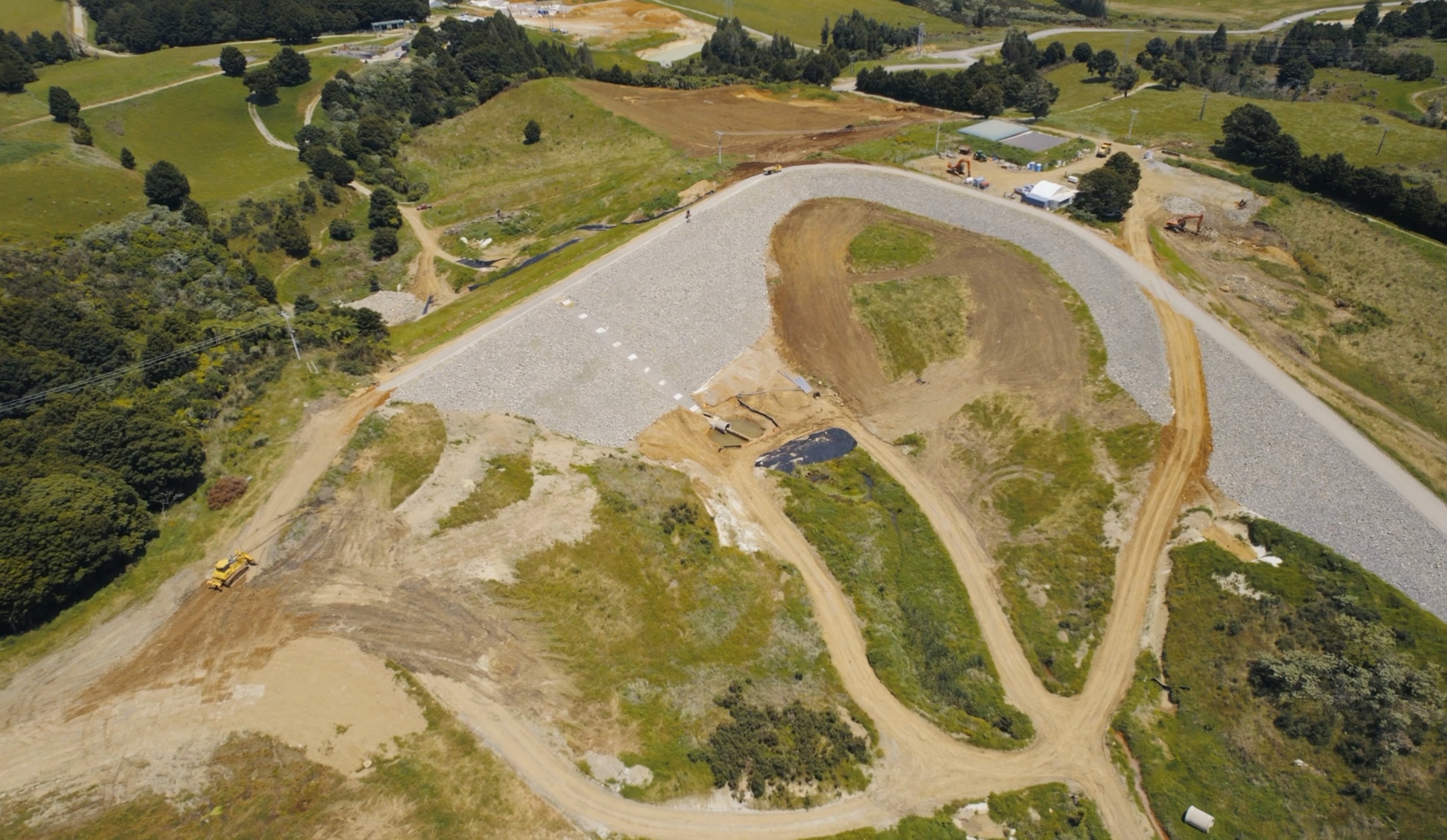 Aerial view of Matawii Dam during construction. The entire area behind the dam wall (the bottom half of the photo) is now under water. Photo / Kānoa, MBIE