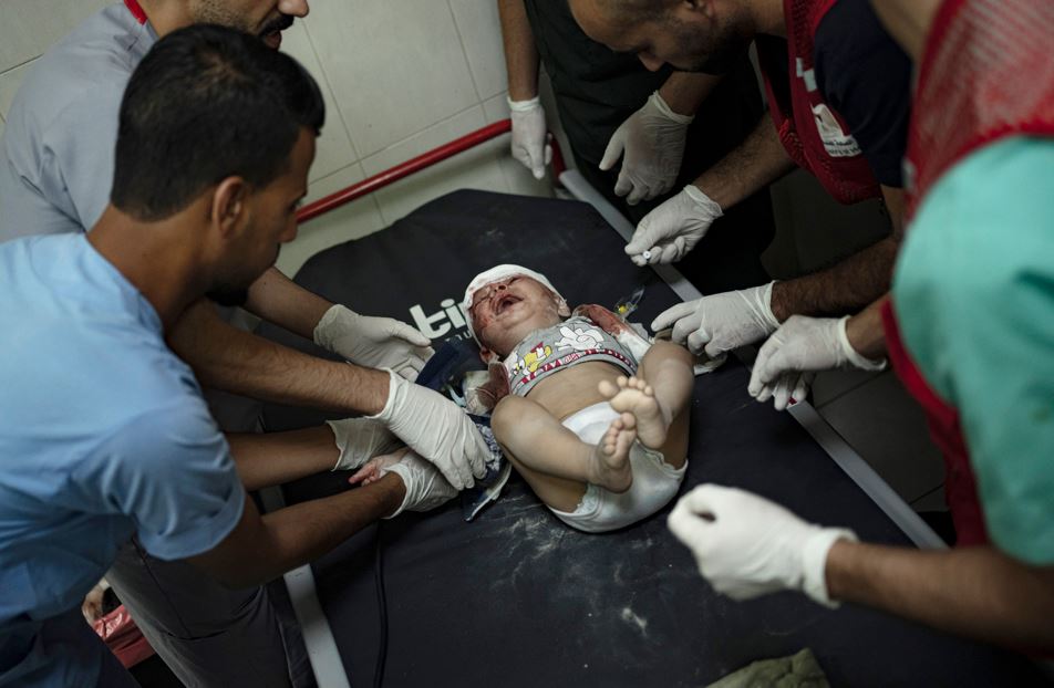 Palestinian medics surround a baby wounded in the Israeli bombardment of the Gaza Strip in Khan Younis. Photo / AP