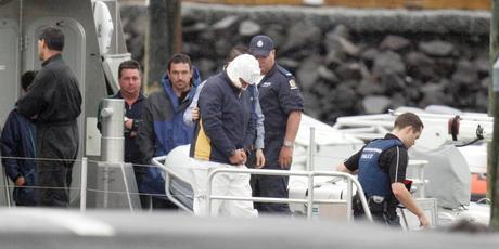 Police leading Nathan Boulter in handcuffs from a police launch at Mechanics Bay after his arrest on Great Barrier Island. Photo / Michael Craig