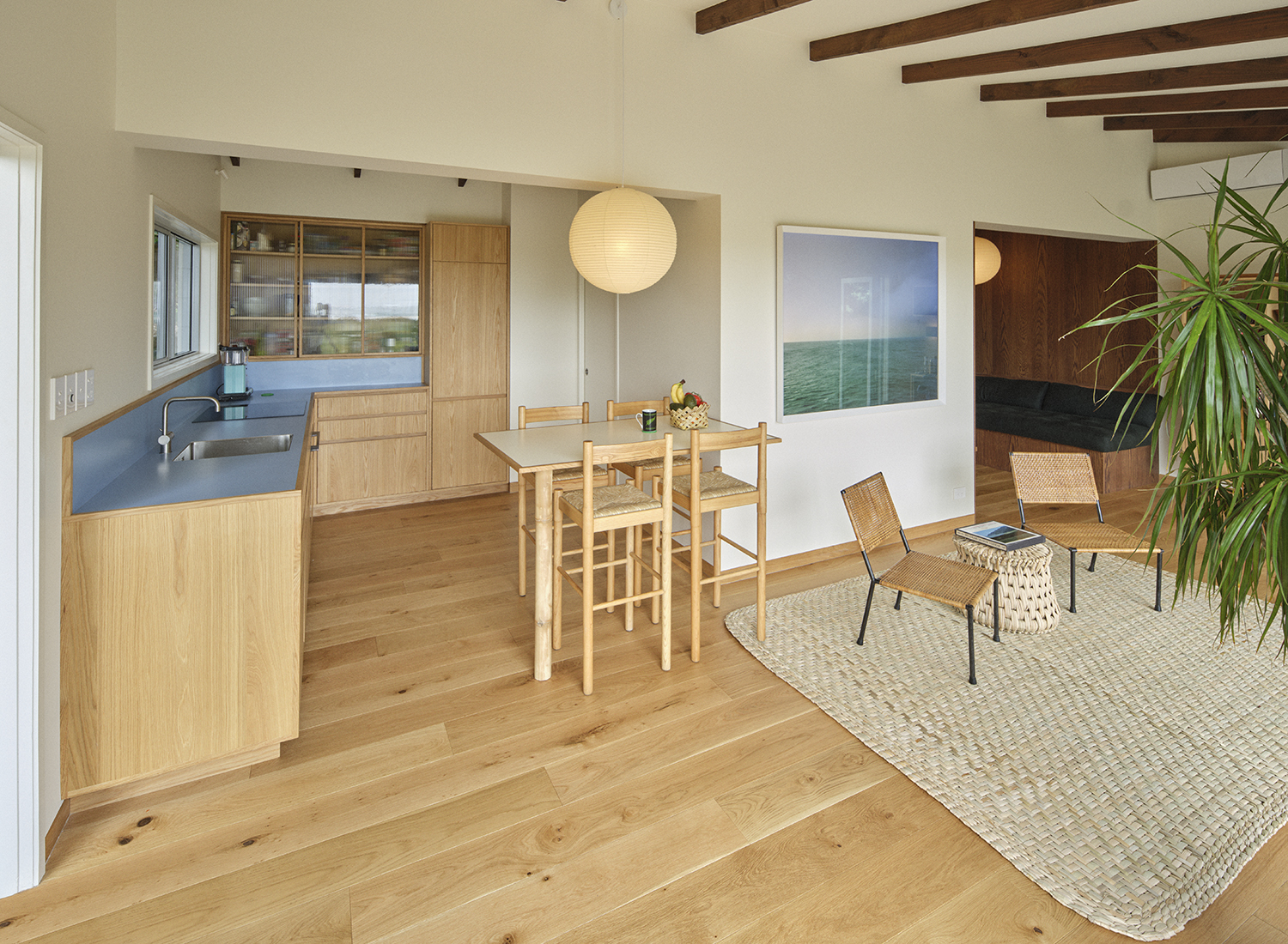 A golden glow emanates from the living area with the use of warm oak timber flooring. One of Derek Henderson’s landscapes hangs in the living room area. Photo / Derek Henderson