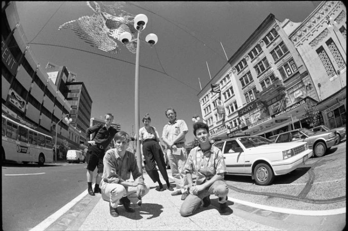 1990 Project photographers Stuart Page, Chris Matthews, Ans Westra, Miles Hargest and Paul McCredie in the central median of Queen Street between the Kerridge Odeon Theatre Centre and the Civic Theatre. Photo / Auckland Libraries Heritage Collections