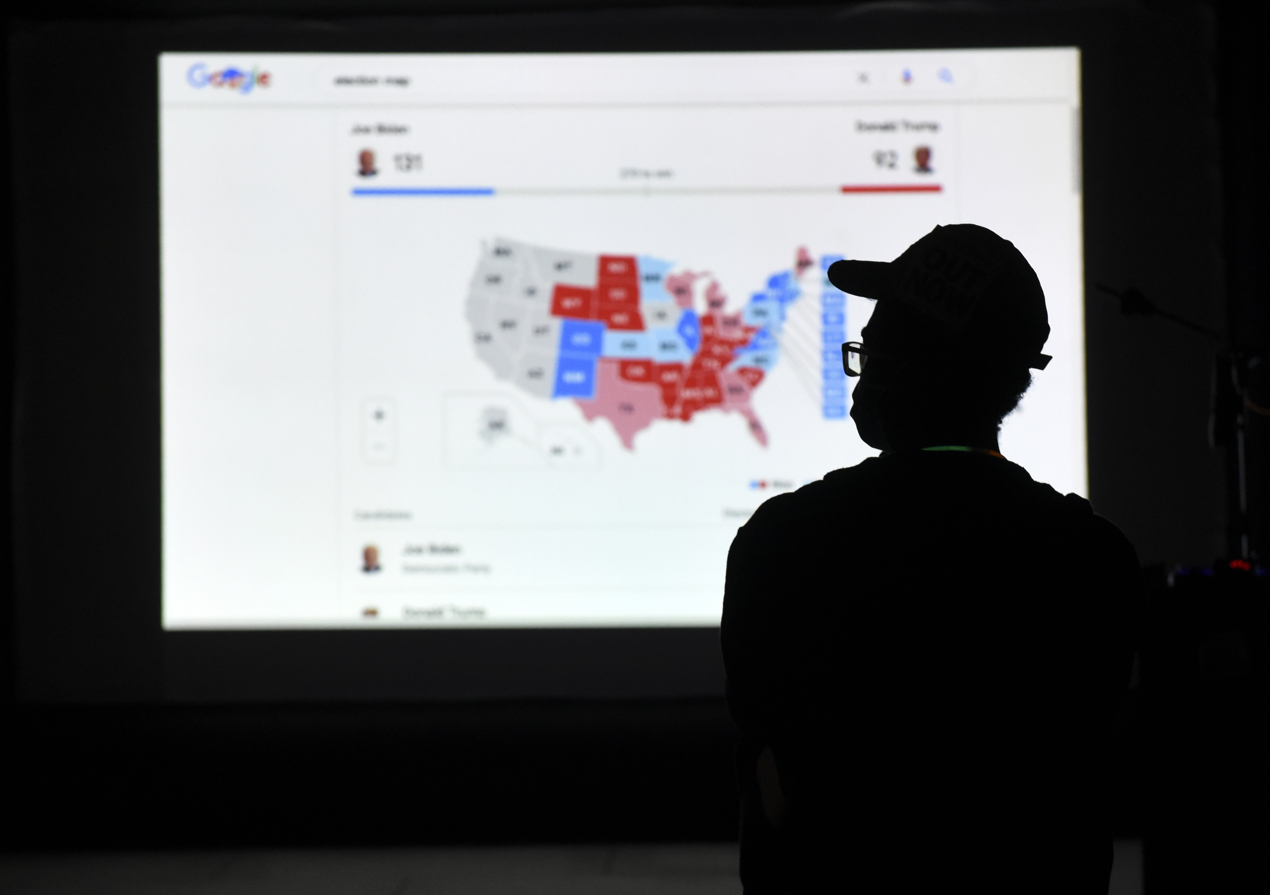 A man watches results come in on a screen set up at an election night gathering. Photo / AP