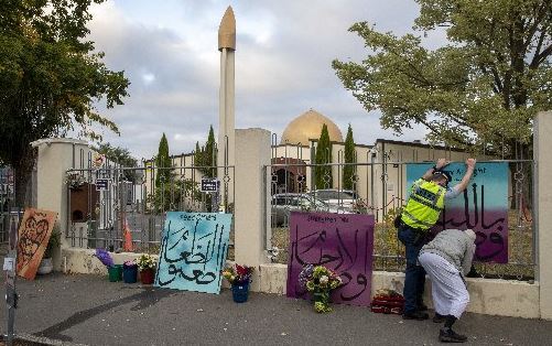 A police officer helps to attach messages to the fence at the Al Noor mosque in Christchurch on the first anniversary of the terror attacks. Photo / Mark Mitchell
