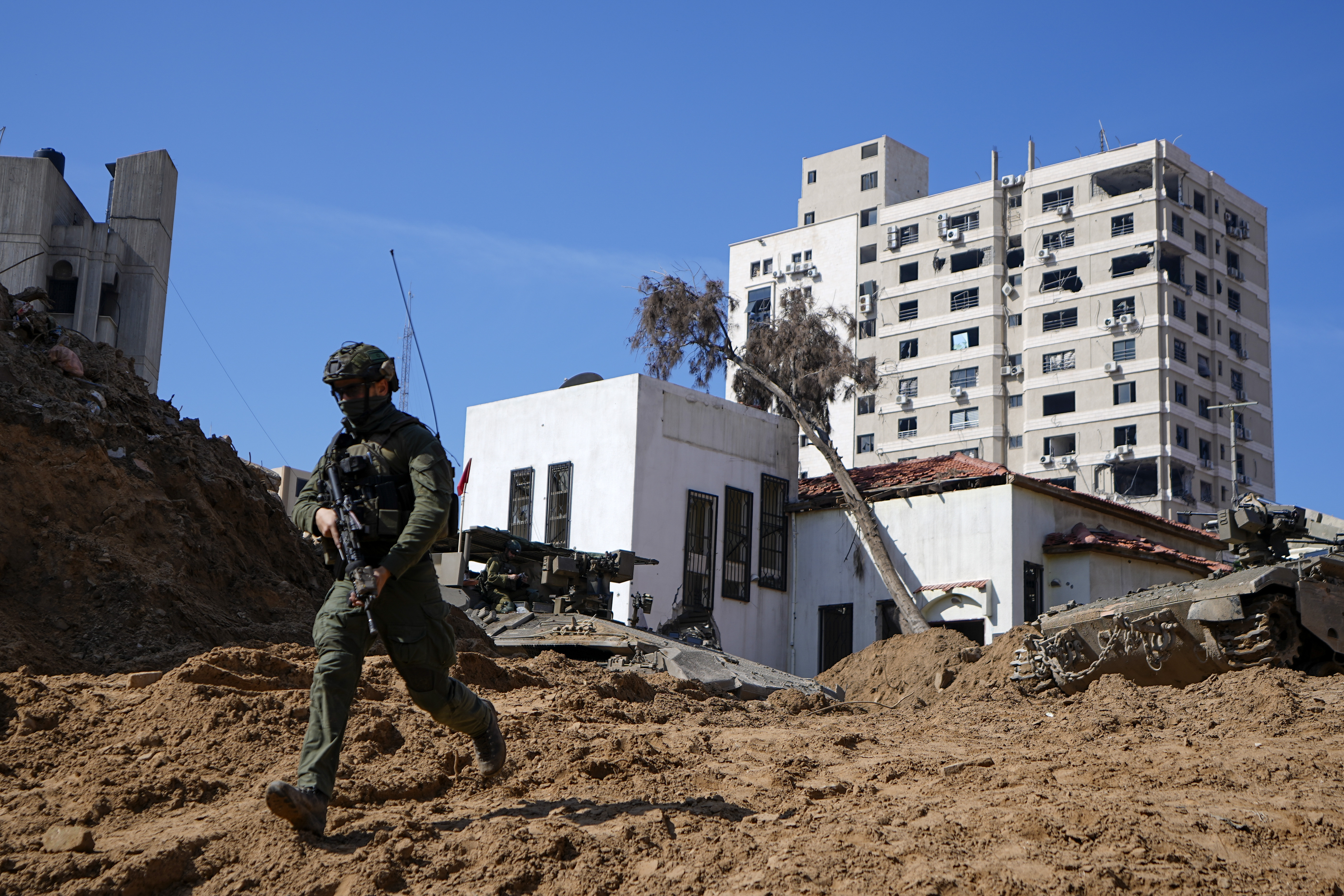 An Israeli soldier runs down a crater-like hole giving way to a small tunnel entrance into the UNRWA compound. Photo / AP