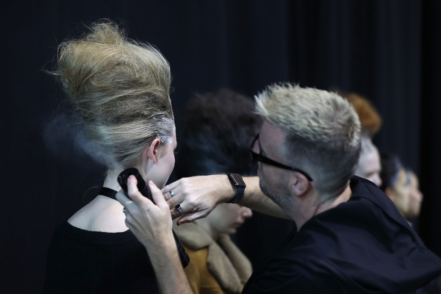 Renowned hairstylist Michael Beel sprays coloured hairspray on a model’s up-do at Kiri Nathan. Photo / Getty Images