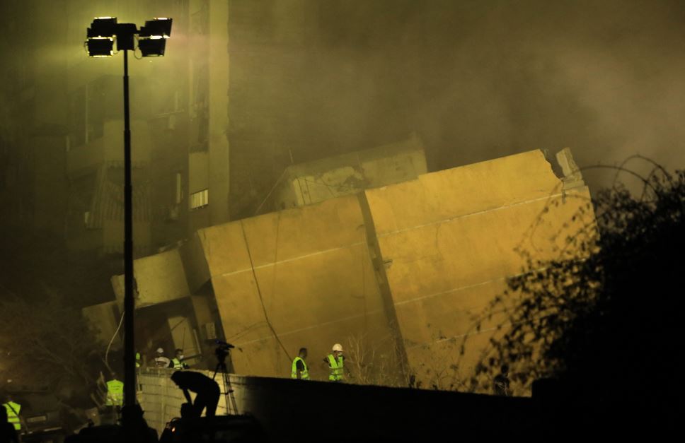 Rescuers stand outside a builiding destroyed in an Israeli air strike in the Haret Hreik neighbourhood of Beirut's southern suburbs. Photo / AFP