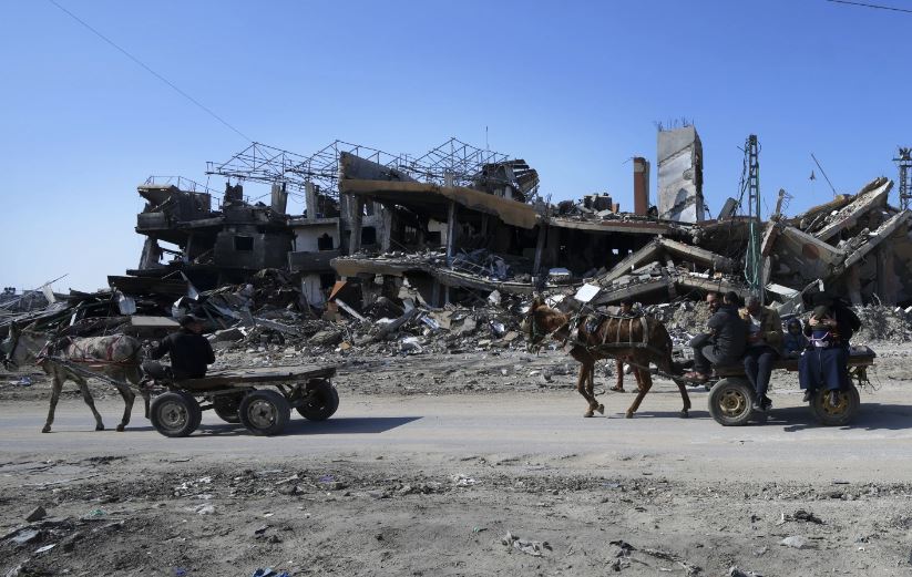 Palestinians ride on donkey carts through destruction from the Israeli bombardment at the main road of Salah el Dein in the Maghazi refugee camp, central Gaza Strip on February 16. Photo / AP