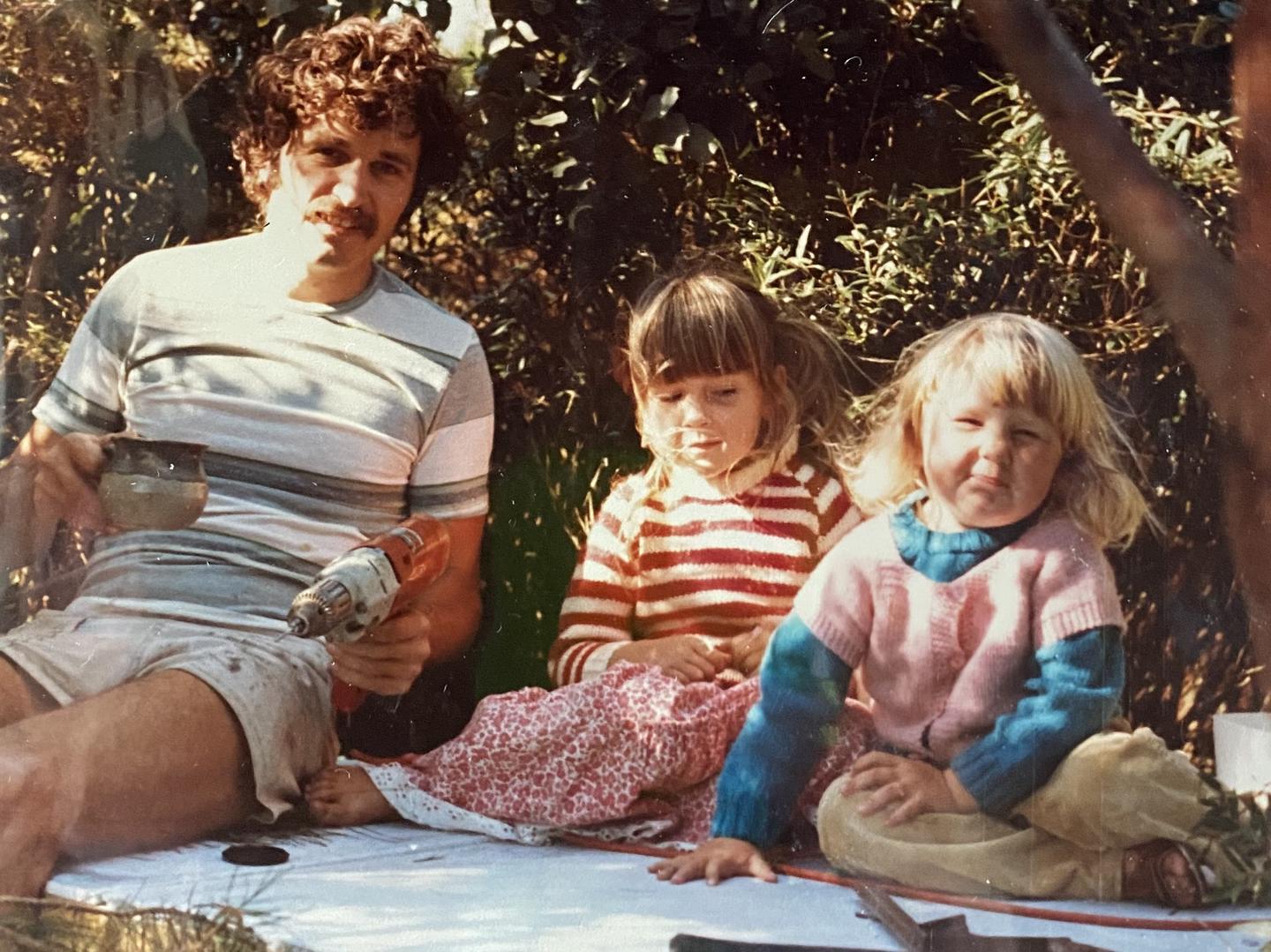 Dr Logan McLennan in 1984, building a tree house with daughters Jaime and Ana.