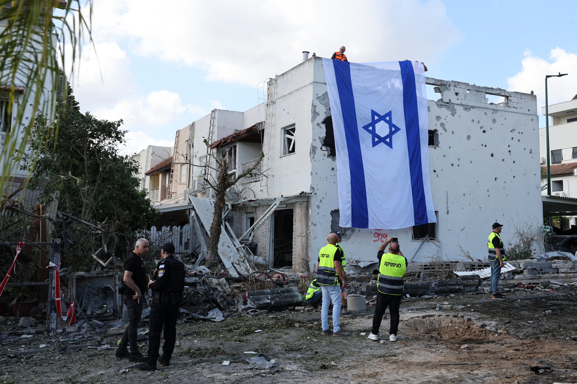 An emergency worker takes a photograph of an Israeli flag on the wall of a damaged building in Kiryat Bialik in the Haifa district of Israel. Photo / AFP