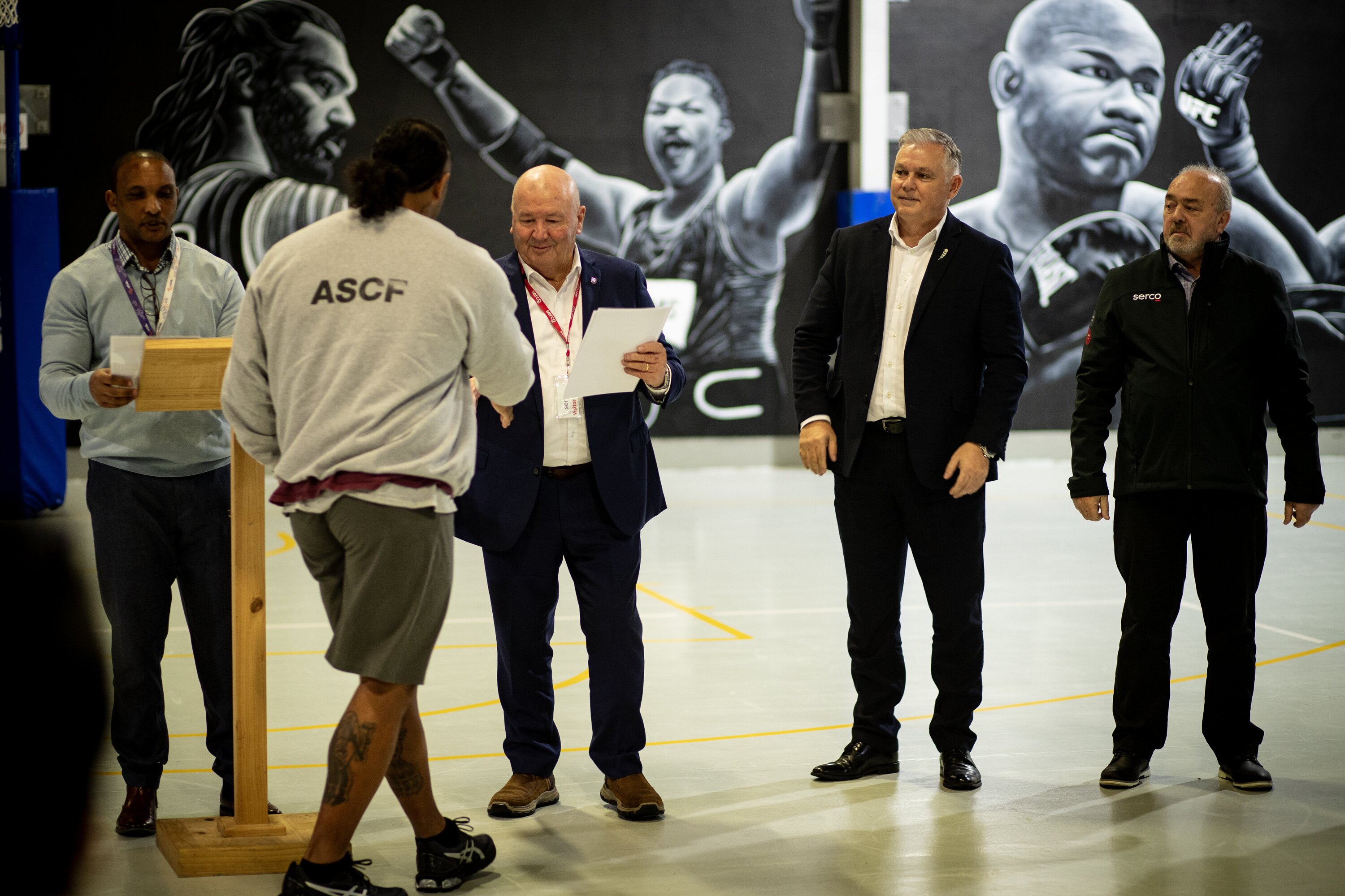 Sir Graham Lowe hands out certificates with Minister of Corrections Mark Mitchell during a prison rehab course graduation.