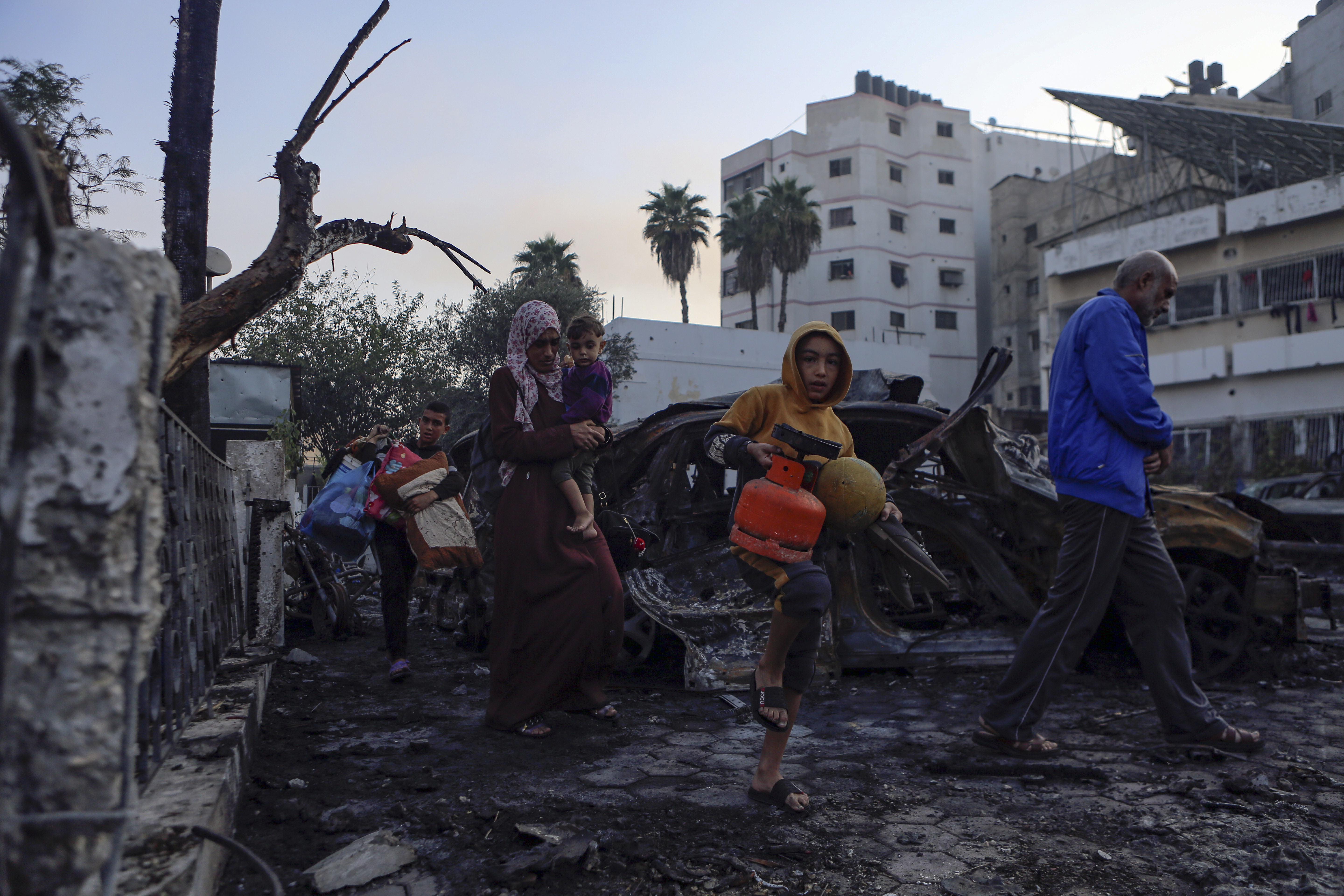 Palestinians carry belongings as they leave al-Ahli hospital, which they were using as a shelter, in Gaza City. Photo / AP
