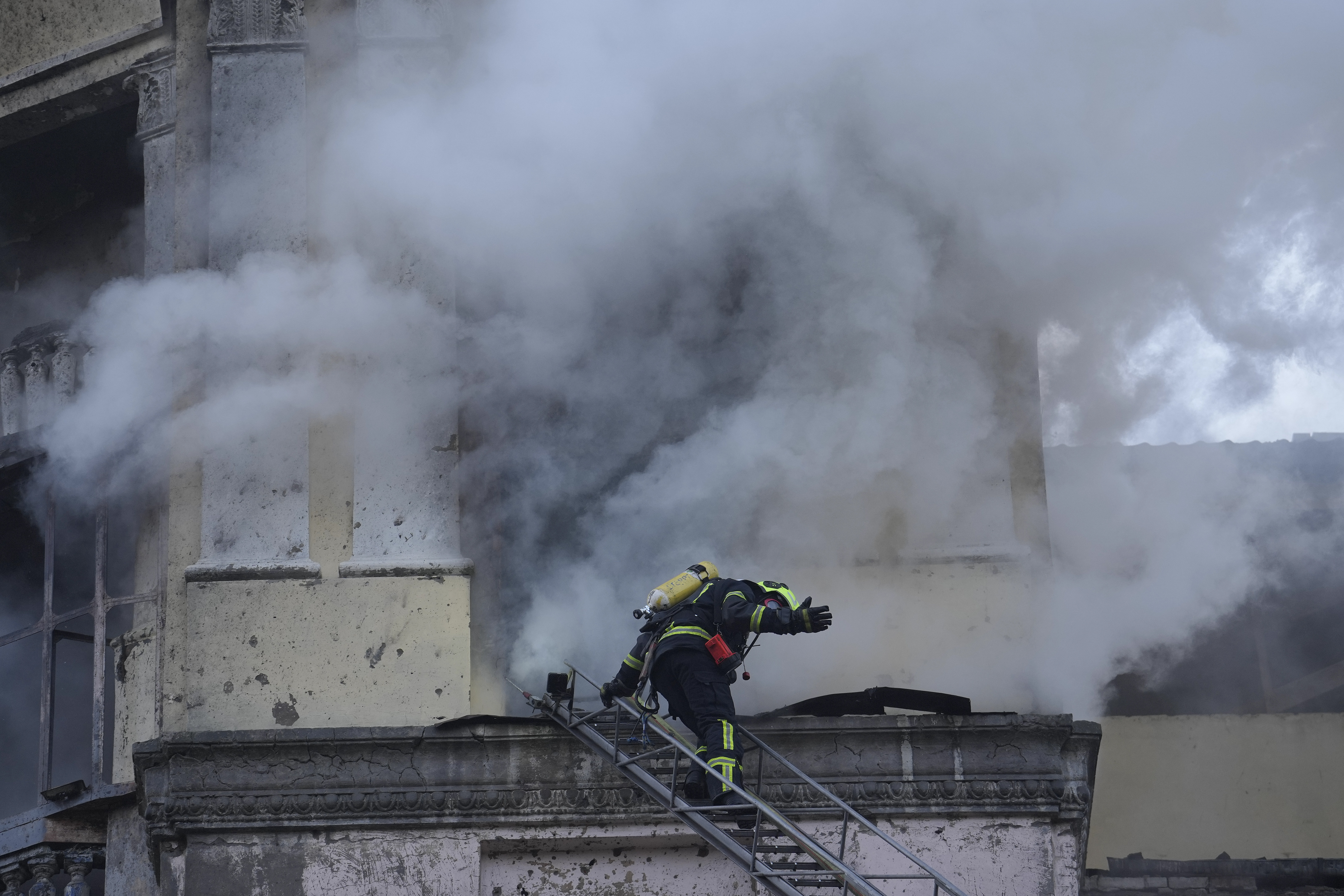 A firefighter gestures as he prepares to enter a building at the site after a Russian attack in Kyiv, Ukraine. Photo / AP