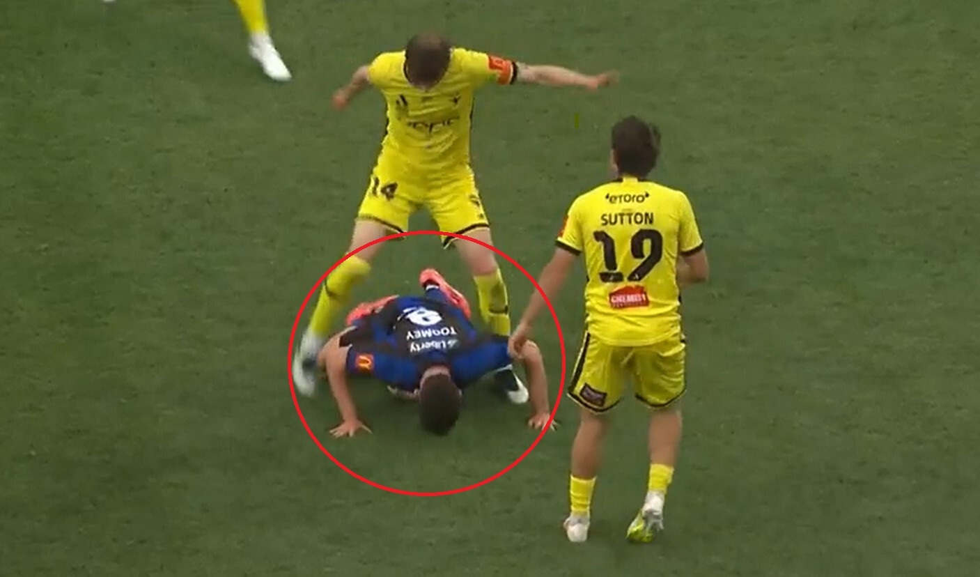 Phoenix captain Alex Rufer earns a yellow card by kicking at the ball while Auckland FC's Luis Toomey is in the way. Photo / Sky TV