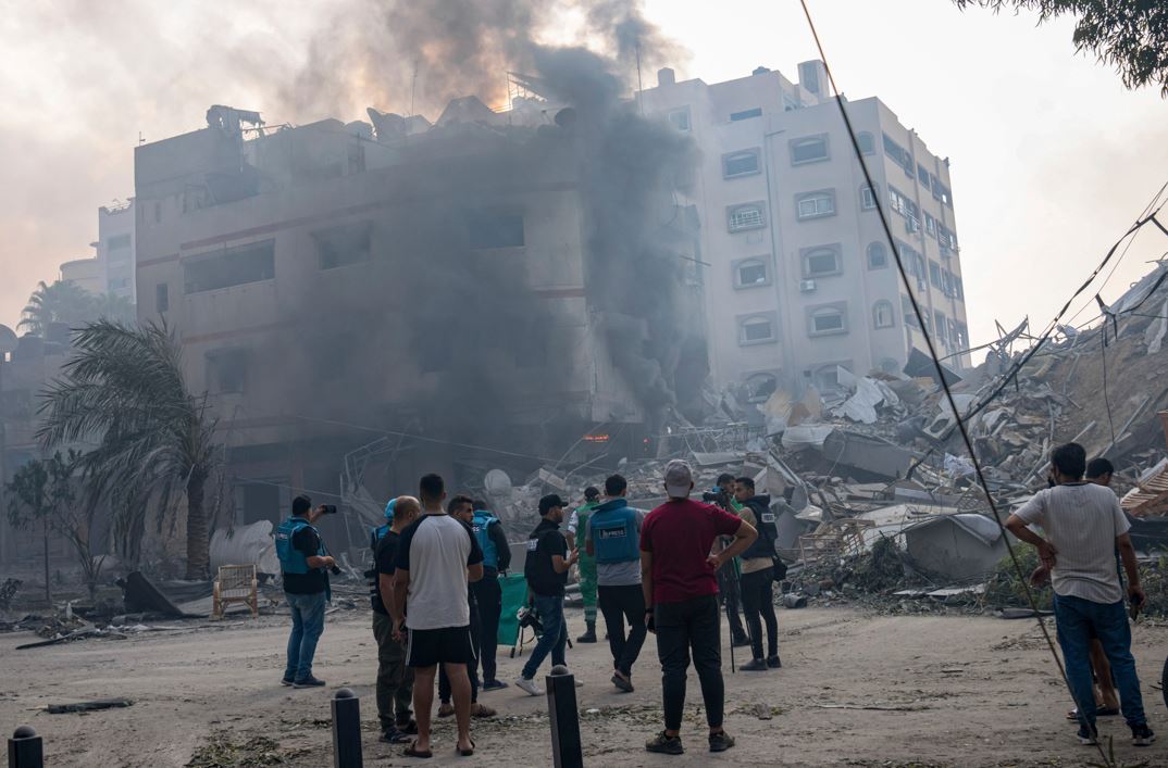 Journalists watch as Palestinians inspect the rubble of a building after it was struck by an Israeli airstrike, in Gaza City. Photo / AP