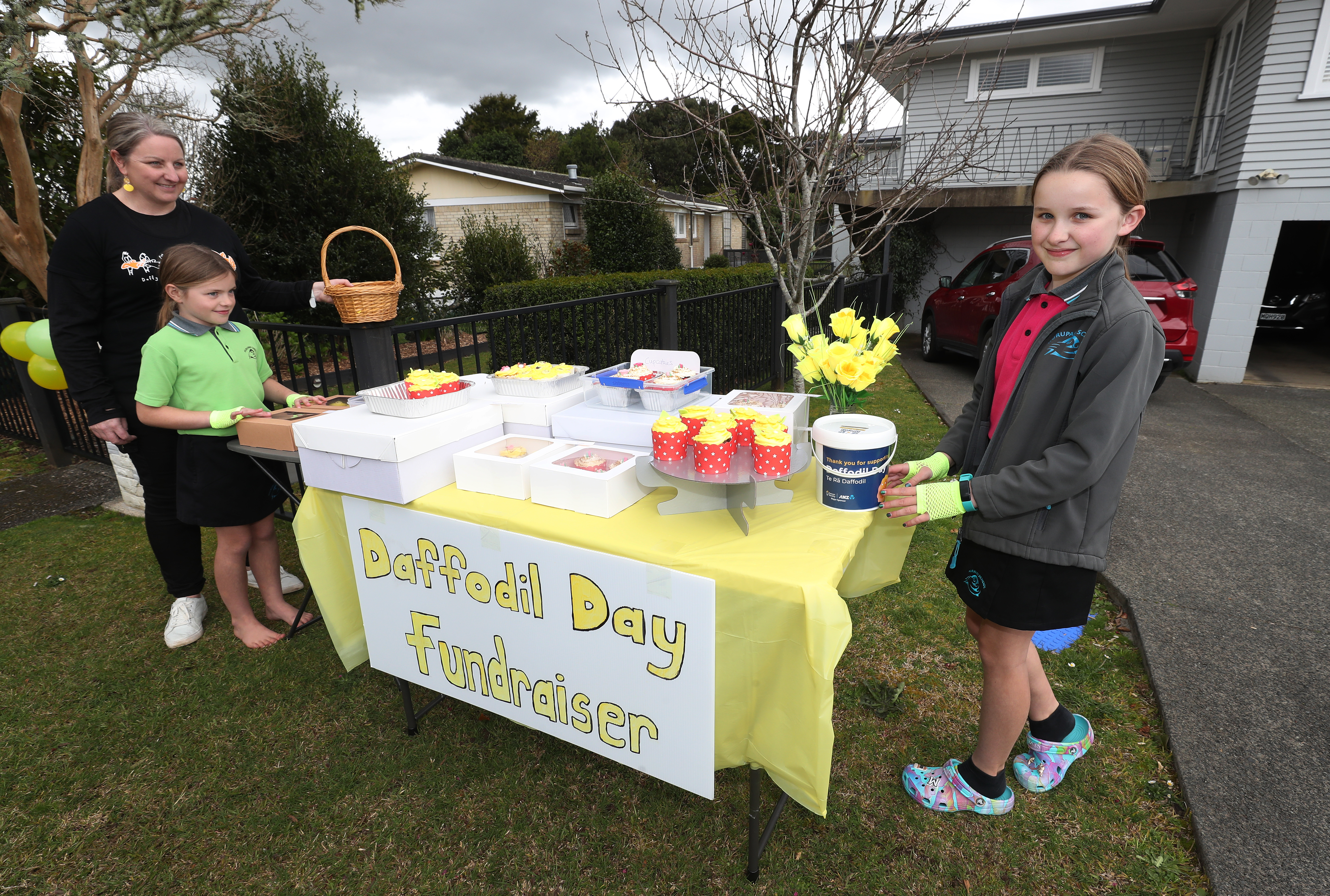 Jo Hunter helps daughters Sophie (left) and Madison man their Daffodil Day cupcake stand. Photo / Michael Cunningham