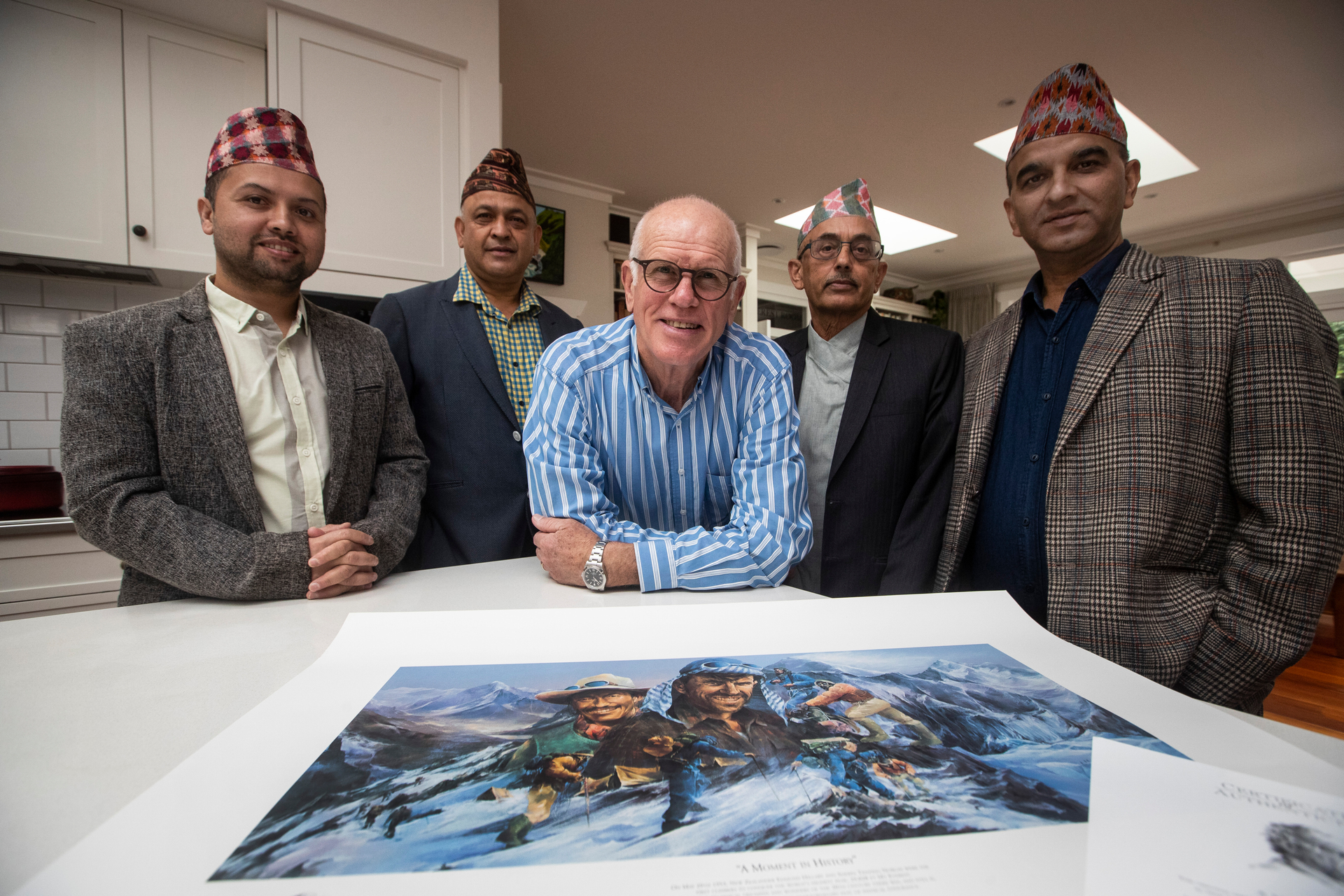 Bikash Pokhrel (left), Dinesh Khadka, Peter Hillary, Uddhav Adhikary and Binod Acharya with a signed poster of Sir Ed and Norgay to be auctioned on Everest Day. Photo / Jason Oxenham