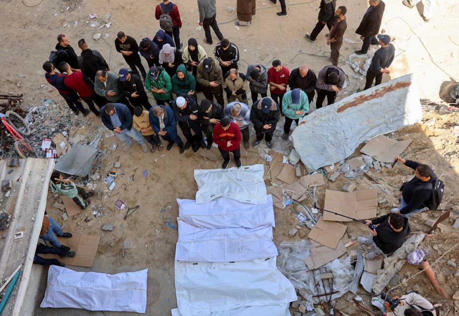 People pray over bodies after Palestinian civil defence workers uncovered corpses buried in the grounds of Al-Shifa hospital in Gaza City. Photo / AFP