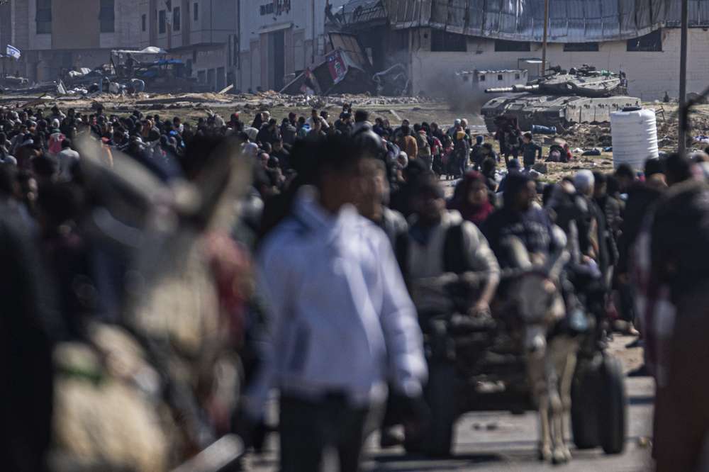 An Israeli army tank takes up position as Palestinians arrive in the southern Gaza town of Rafah after fleeing an Israeli ground and air offensive in the nearby city of Khan Younis. Israel has expanded its offensive in Khan Younis, saying the city is a stronghold of the Hamas militant group. Photo / AP