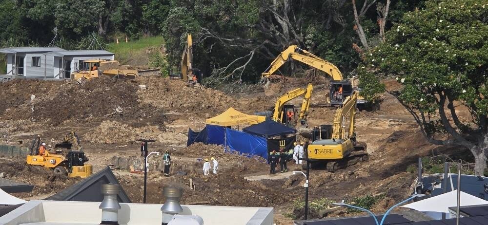 Forensics specialists are seen in white boiler suits on Wednesday morning at the scene of the Mount Maunganui landslide where the operation to recover the remains of the missing is ongoing.
