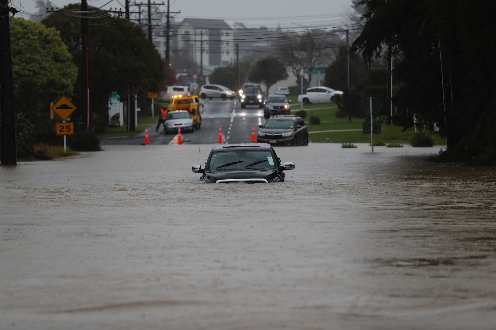 Car underwater and police checking on residents on Oraha Road, Kumeu. Photo / Dean Purcell