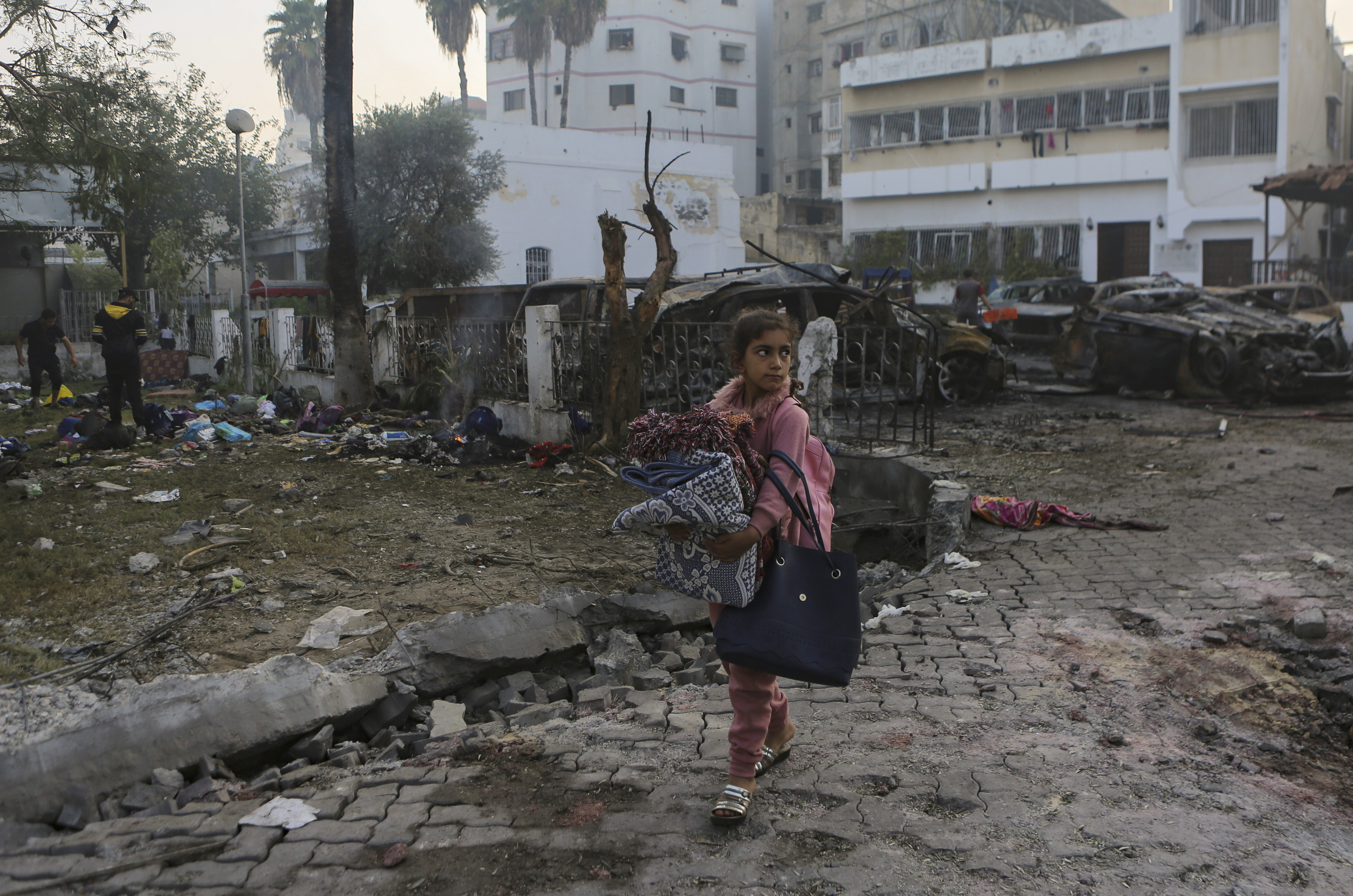 A Palestinian girl carries a blankets as she walks past the site of a deadly explosion at al-Ahli hospital, in Gaza City. Photo / AP