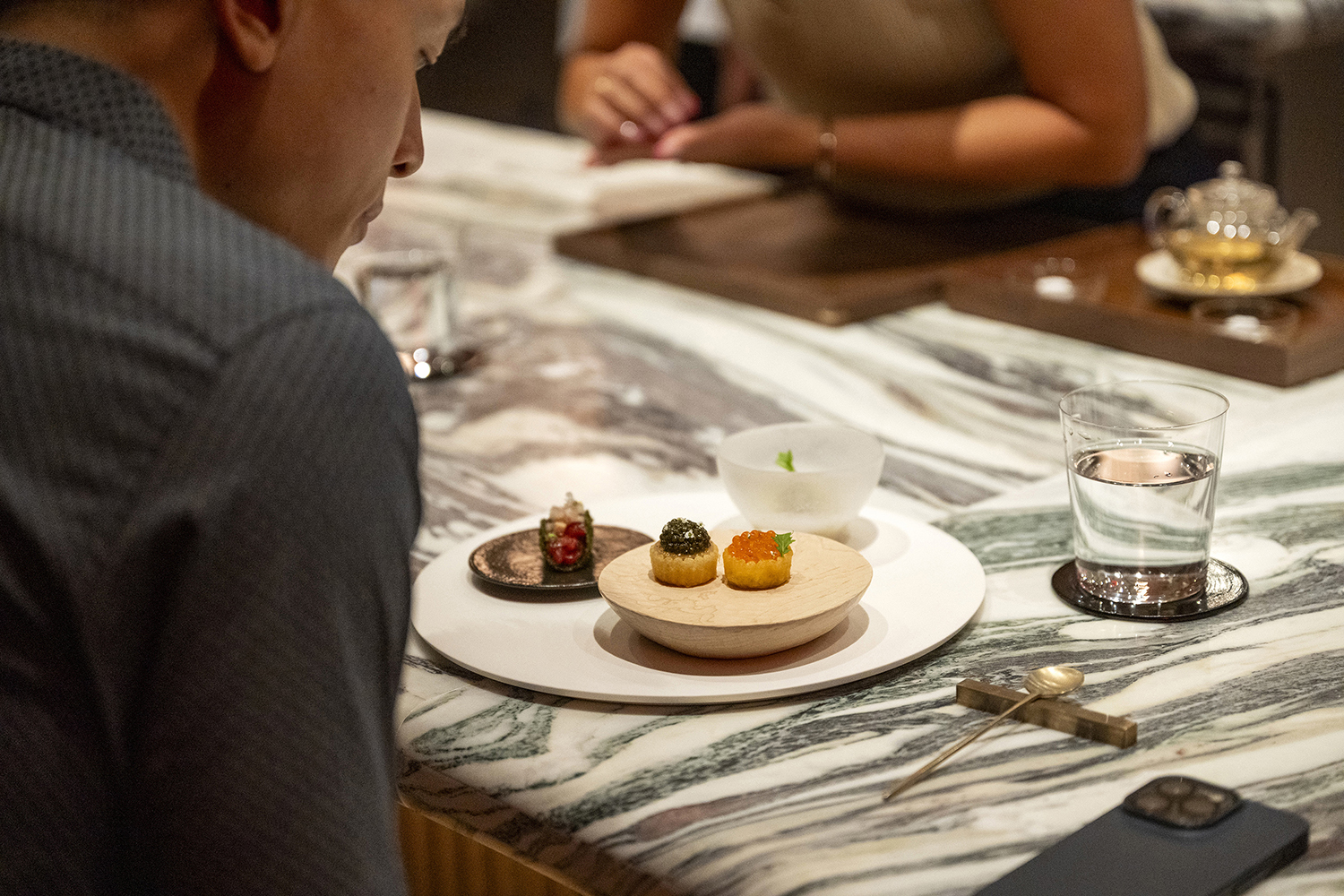 A meal at Bōm starts with two tiny, precise caviar tarts, in New York. Photo / Evan Sung, The New York Times