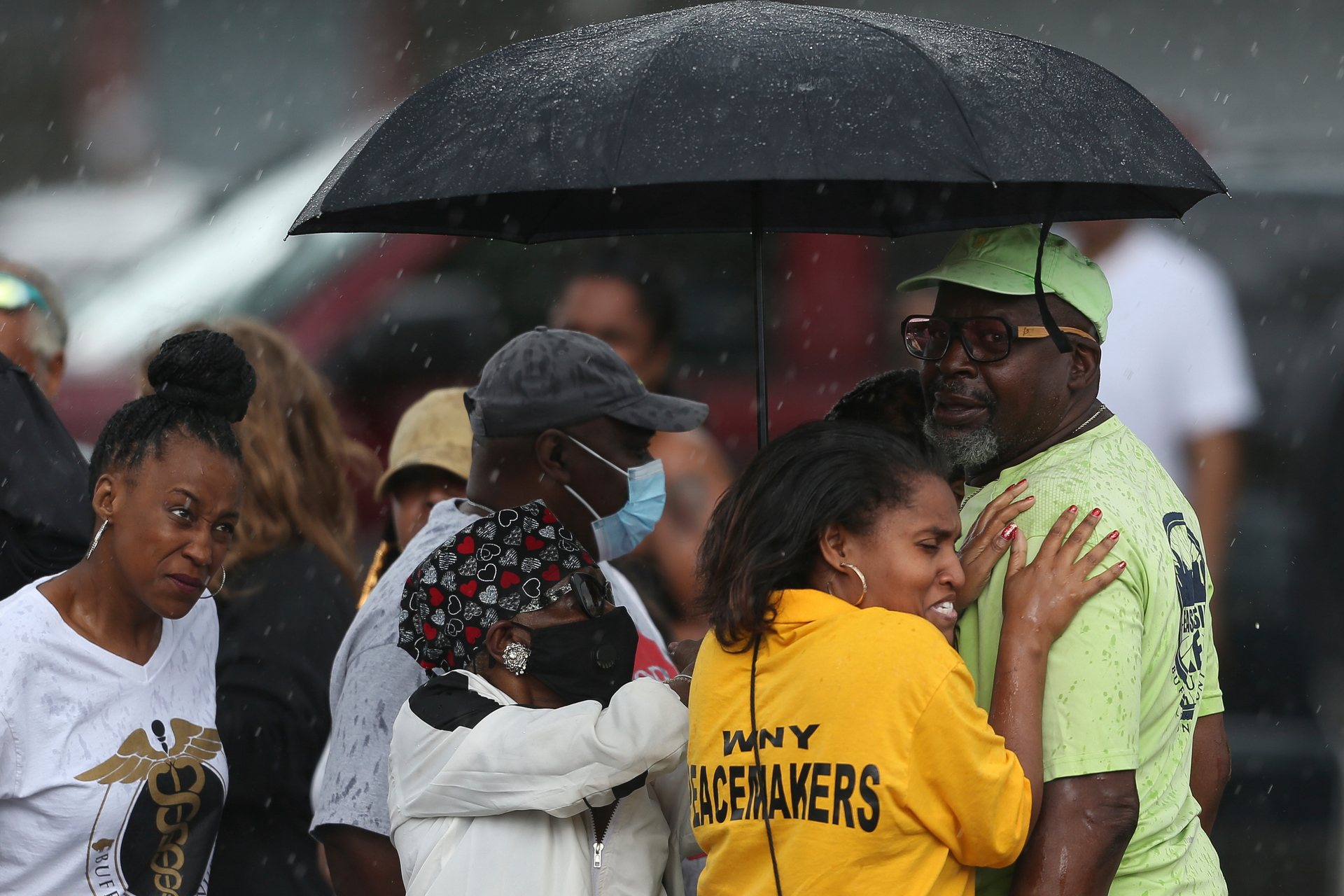 Bystanders gather under an umbrella as rain rolls in after a shooting at a supermarket in Buffalo, New York. Photo / AP