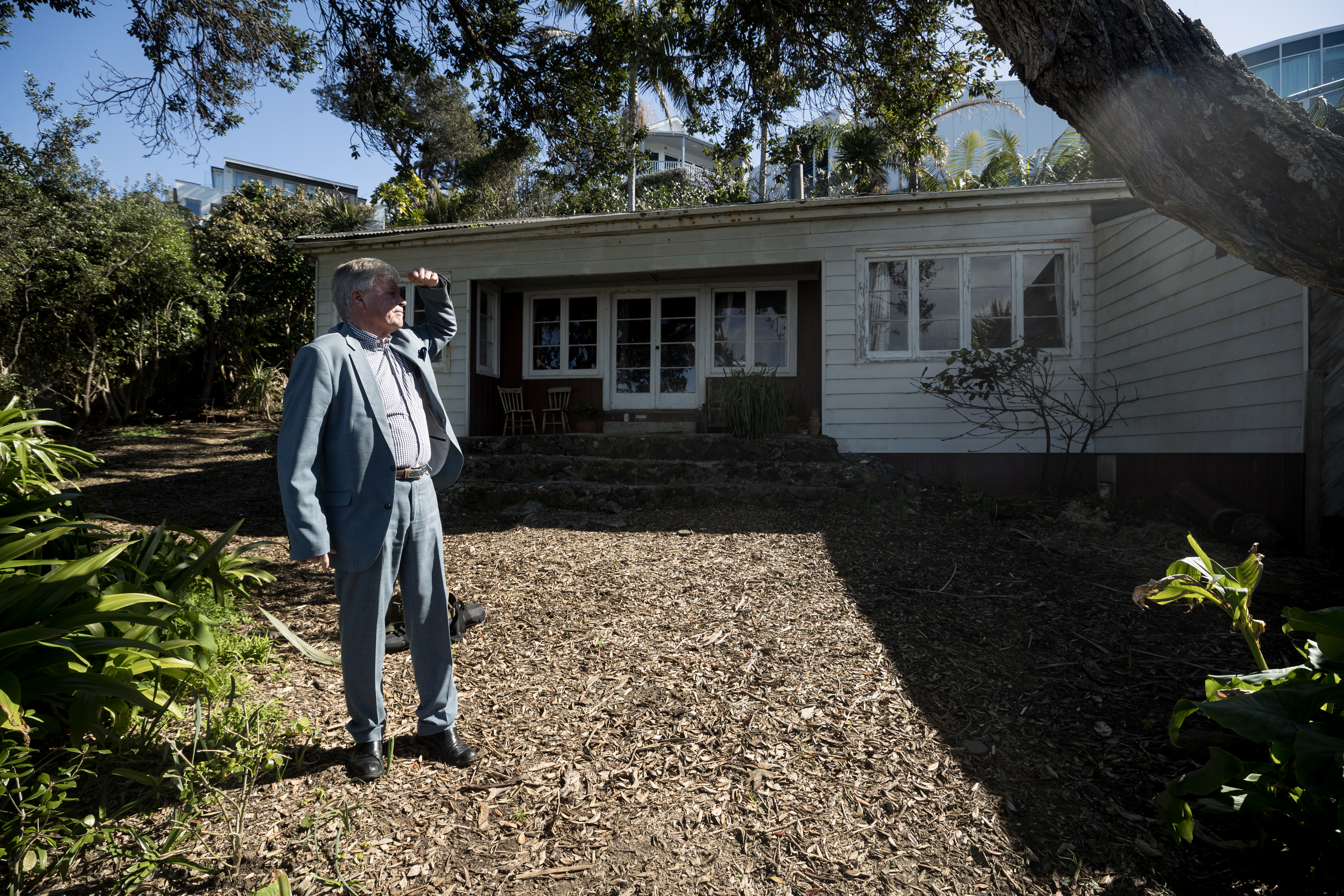 Lawyer Alex Witten-Hannah stands in front of the humble Firth cottage that sits next to a four-storey $13 million mansion. Photo / Dean Purcell