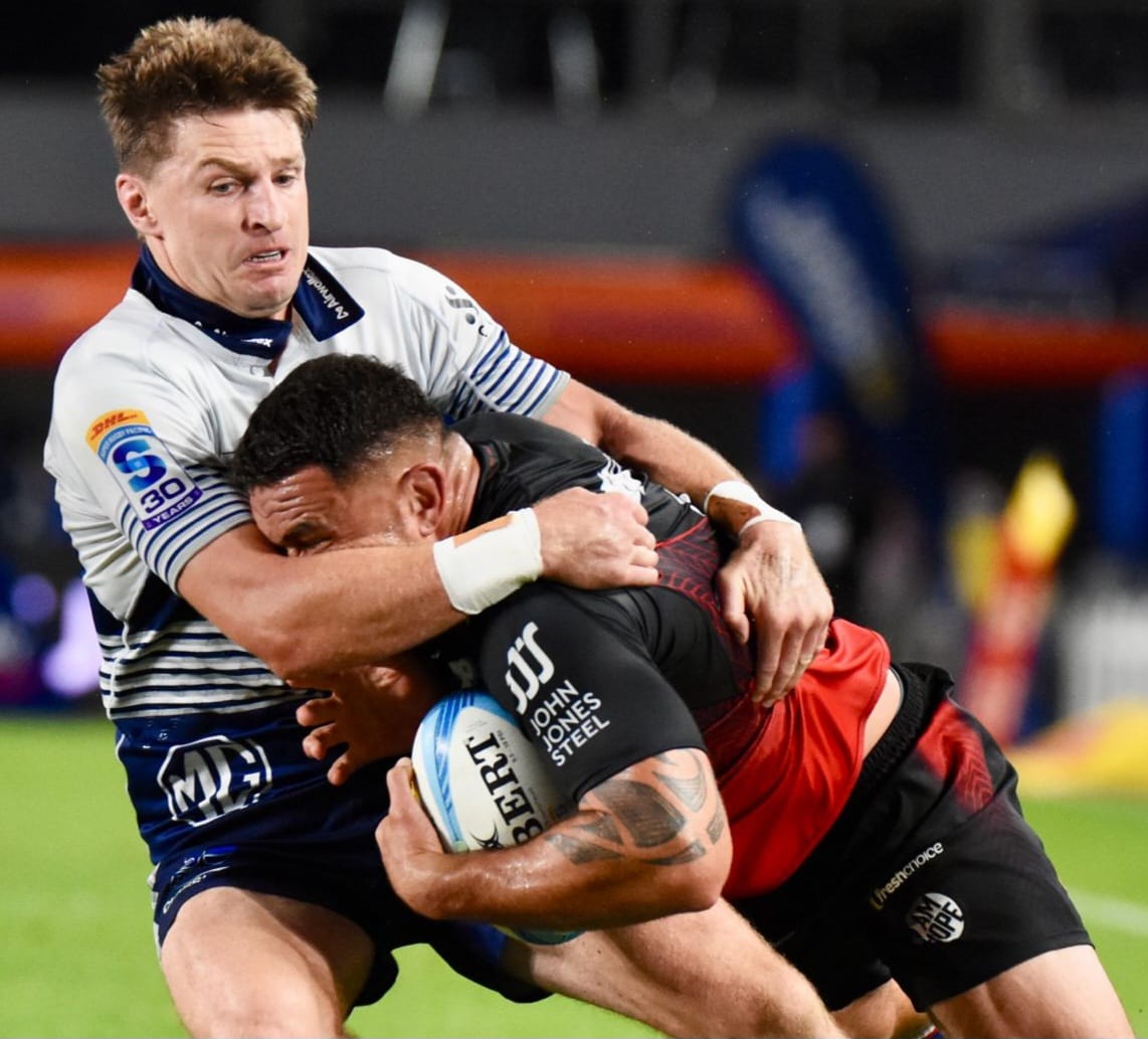 Codie Taylor is tackled by Beauden Barrett. Photo / Brad Roberts
