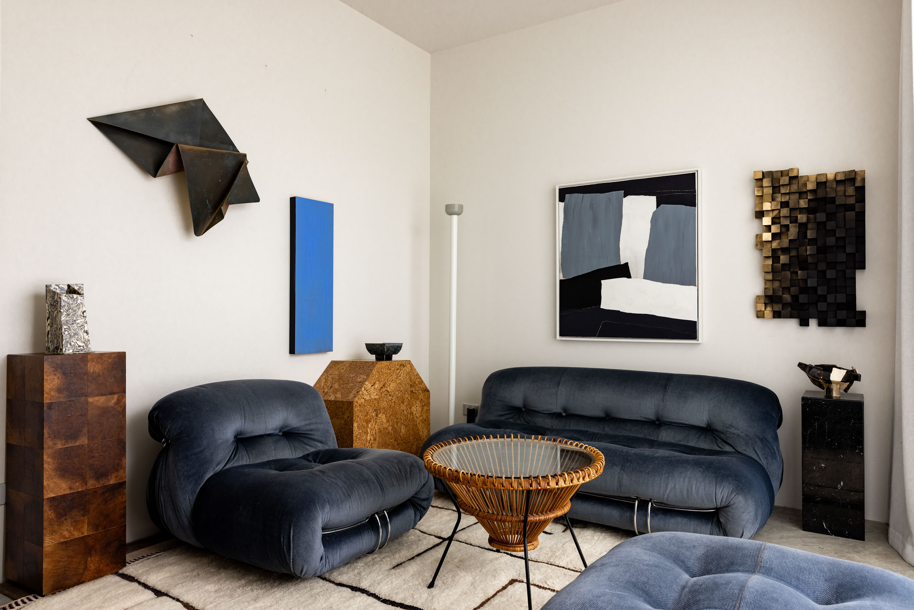 In the living space is a Soriana chair, sofa and pouf by Afra and Tobia Scarpa for Cassina. On the left wall is a brass abstract piece called Shape Shifter by Jodi Newnham. To the right is a contemporary abstract painting called Ultramarine, also by Jodi Newnham. The artwork above the sofa is by Mirjam Lugt. Photo / Babiche Martens