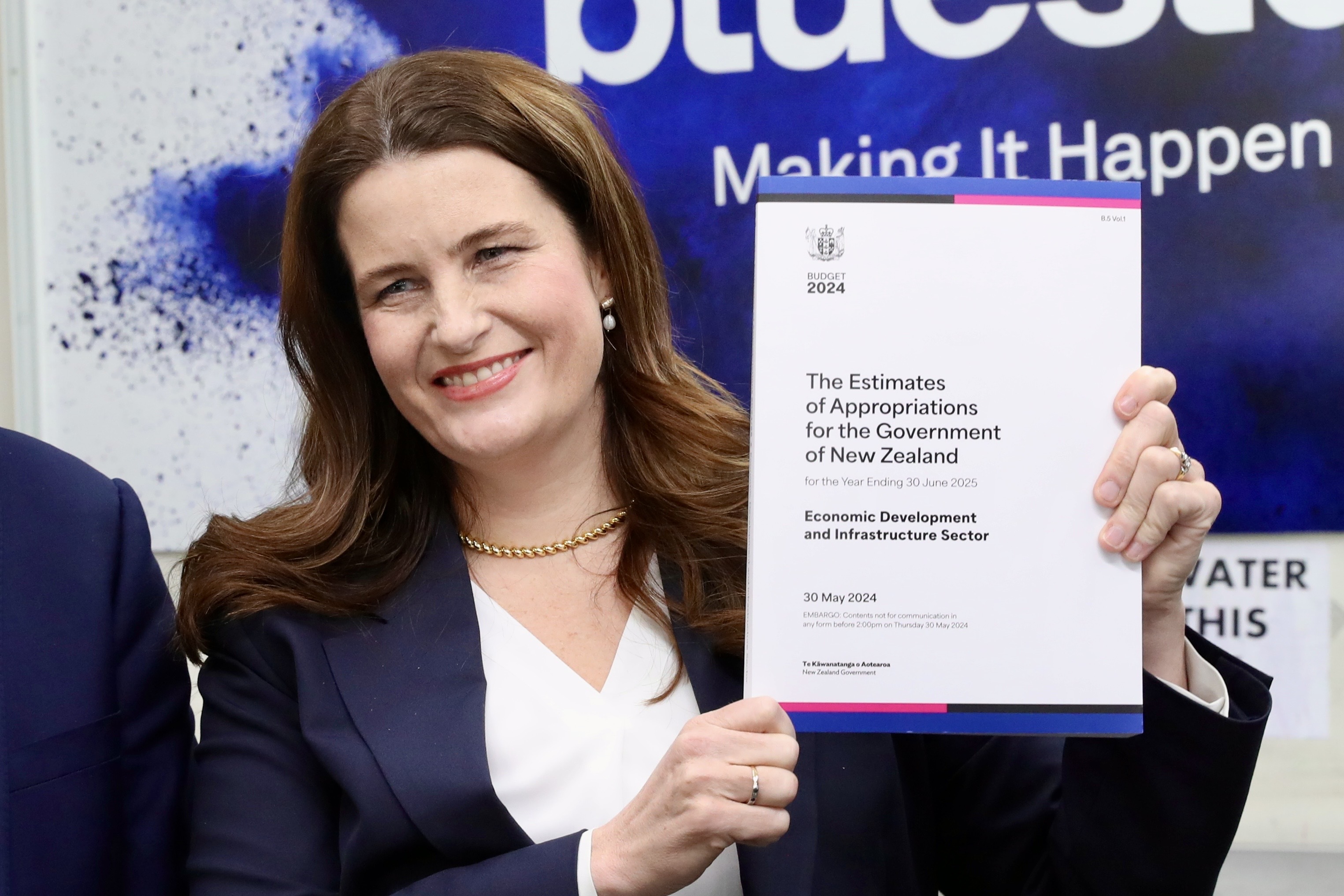 Finance Minister Nicola Willis showed off the cover at Blue Star Printers   in Petone. Photo / Mark Mitchell
