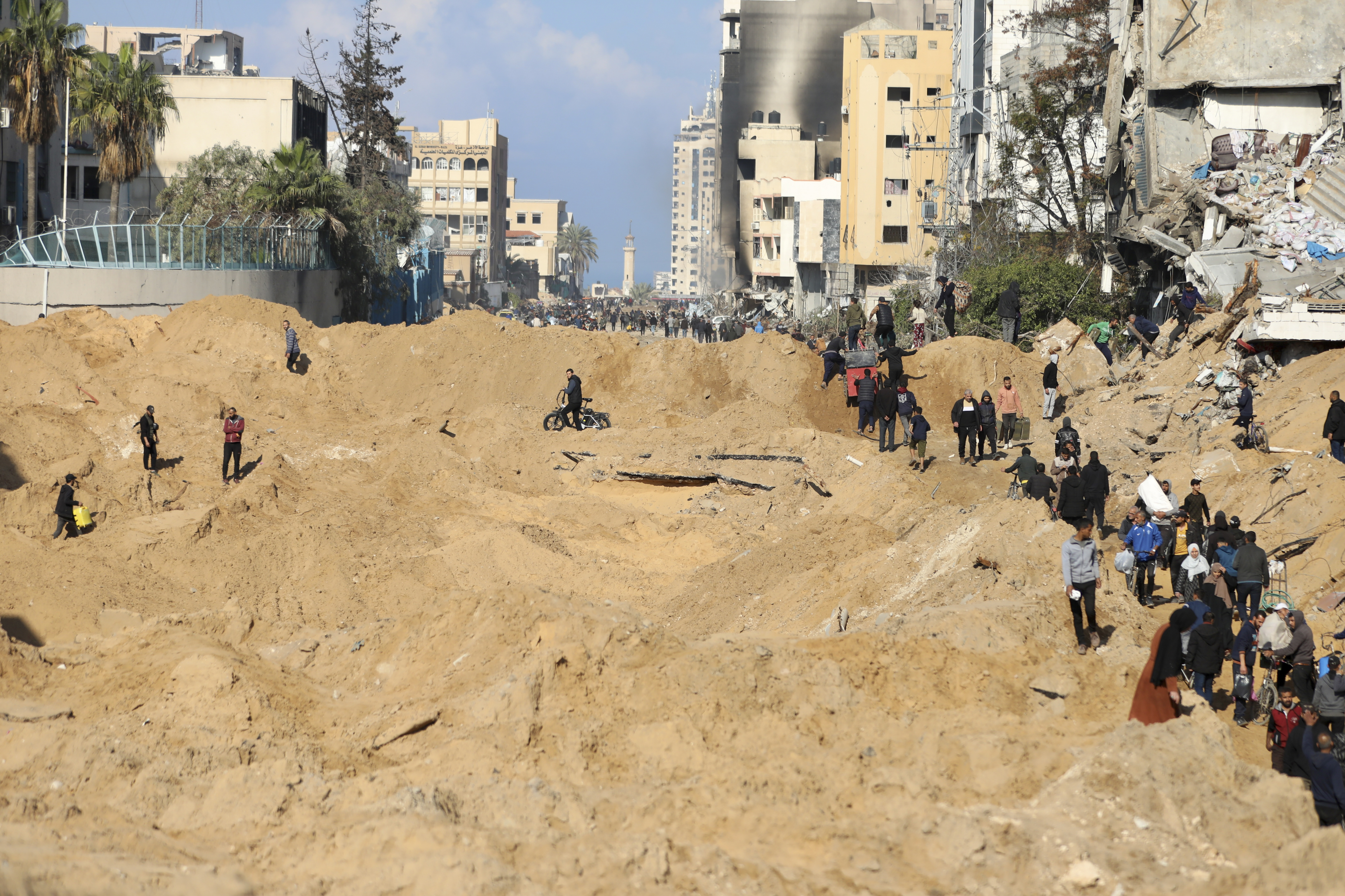 Palestinians walk through the destruction left by the Israeli air and ground offensive on the Gaza Strip in Gaza City. Photo / AP