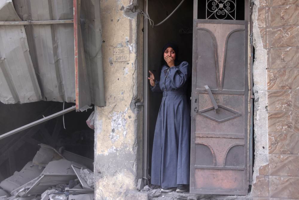 A Palestinian woman standing in a doorway reacts as she watches the aftermath of an Israeli strike that hit Gaza City's southern al-Zeitoun neighbourhood. Photo / Bashar Taleb, AFP