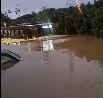 A bus with passengers on board drives through floodwaters in Beachcroft Ave, Onehunga. Photo / Supplied