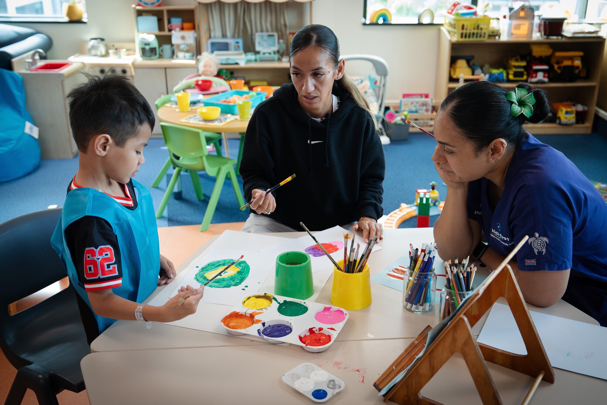 Amias Fitimase works on his painting accompanied by his mother Montoya Fitimase (centre) and Kidz First play specialist Gina Bentley. Photo / Annaleise Shortland