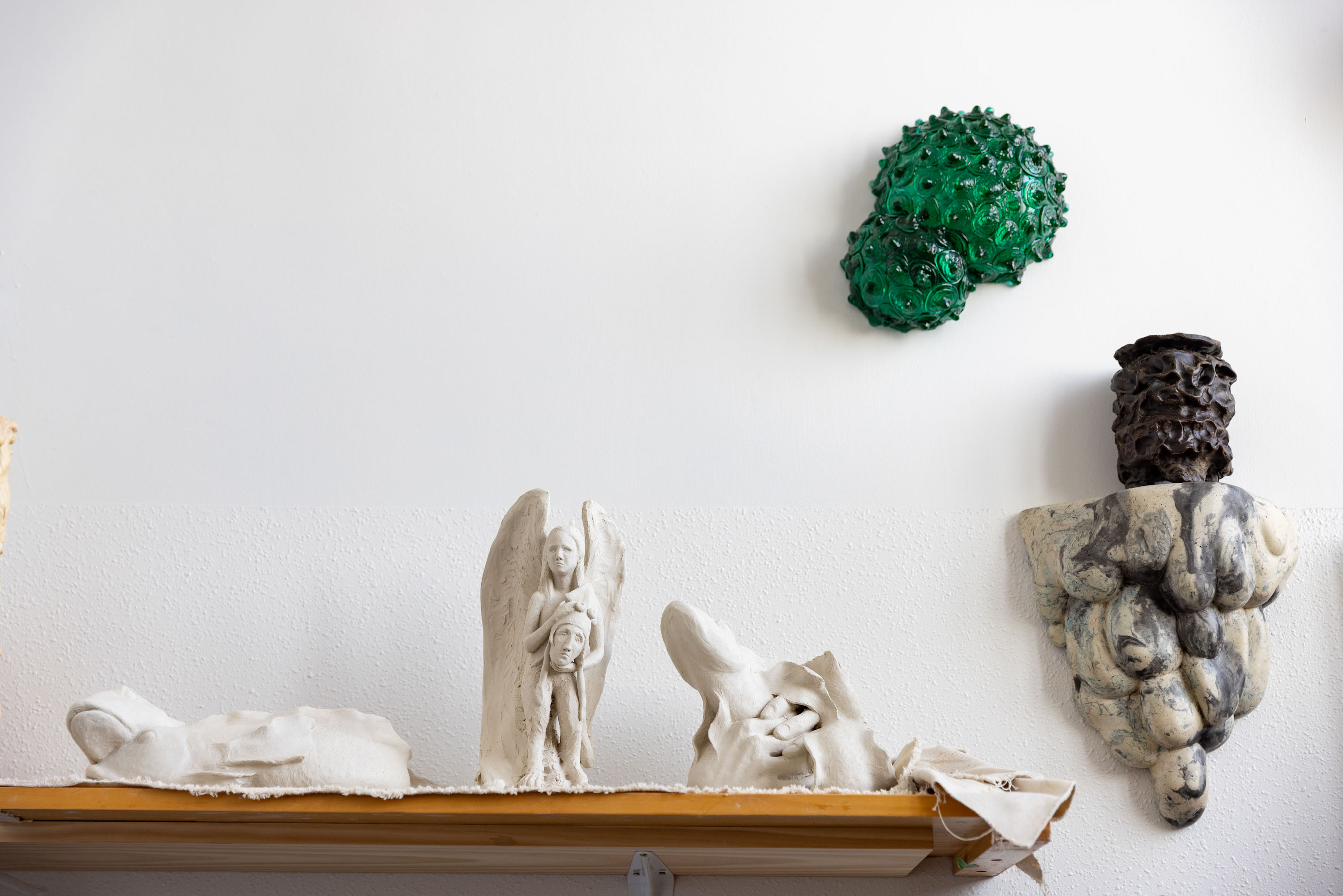 Katherine is working on a series of greenware sculptures. Also pictured is a wax pattern on an early Ghastly R&D wall plinth, and Green Double Bubble No. 2, blown and hot cast Uranium lagoon glass, mirror, birchwood ply, 330 x 100 x 36mm, 2016. Photo / Babiche Martens