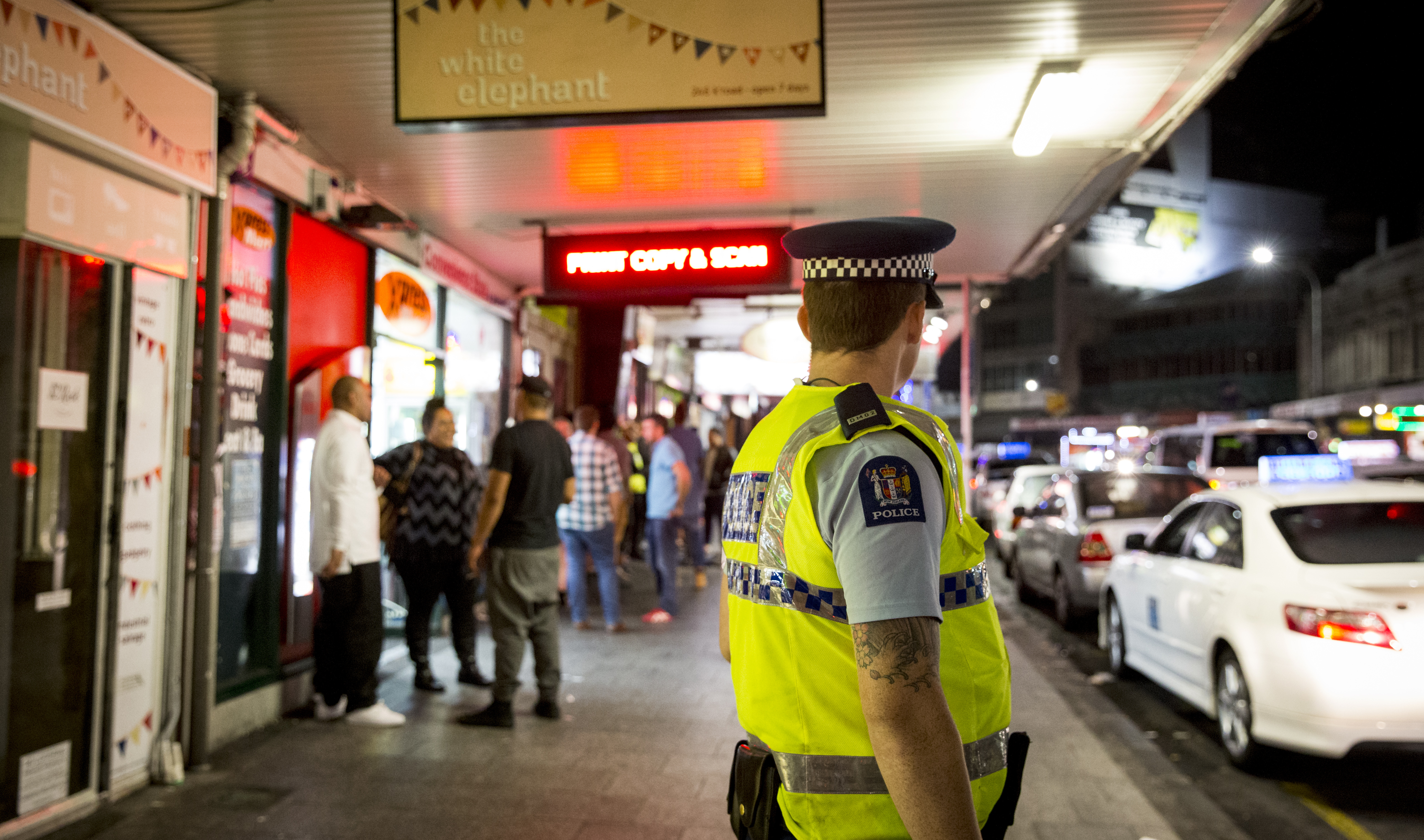 A police officer watches people on Karangahape Rd in Auckland, an area which has seen an increase in foot patrols. Photo / Mike Scott