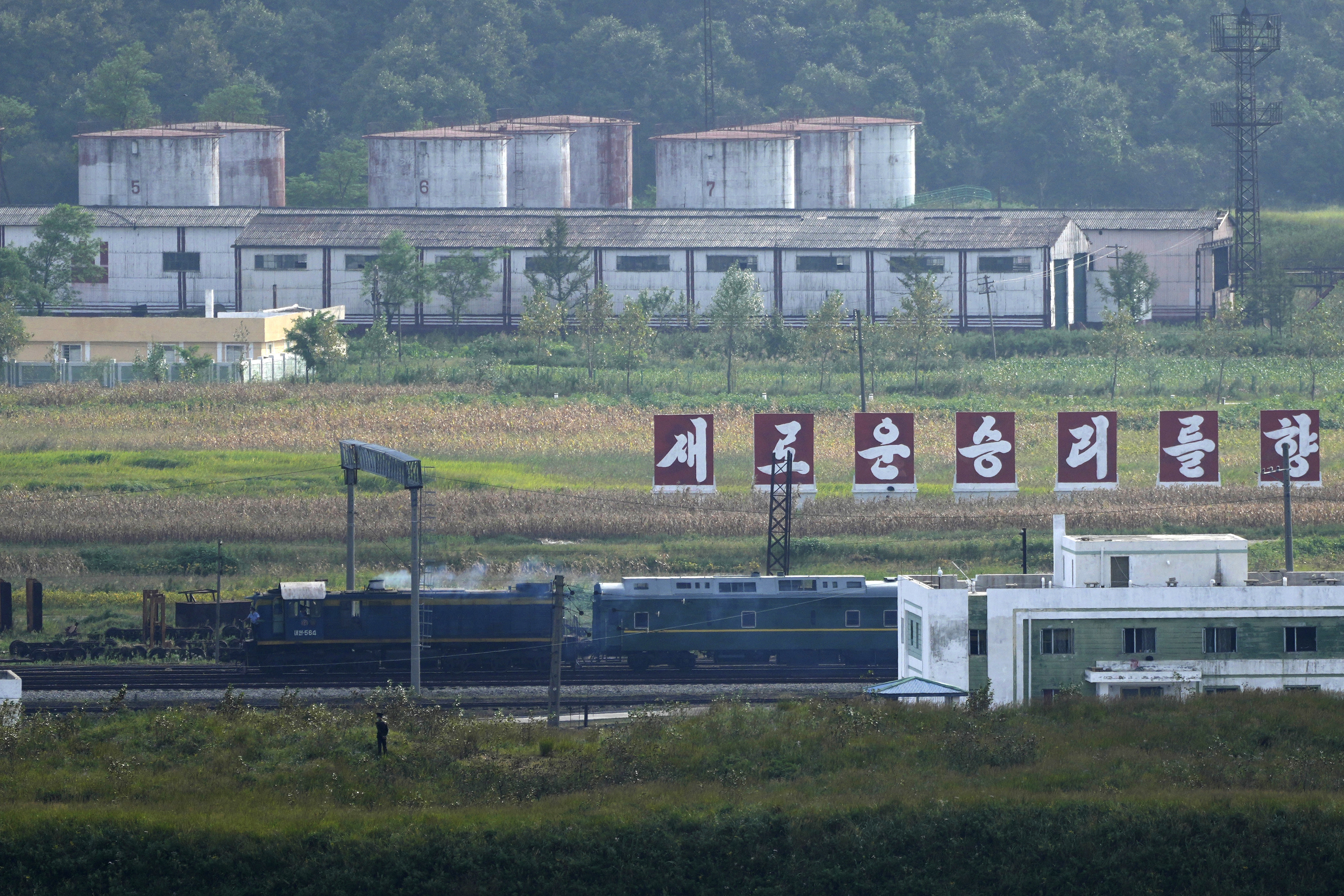 A train resembling one used by North Korean leader Kim Jong Un on his previous travels, is seen steaming by a slogan which reads 