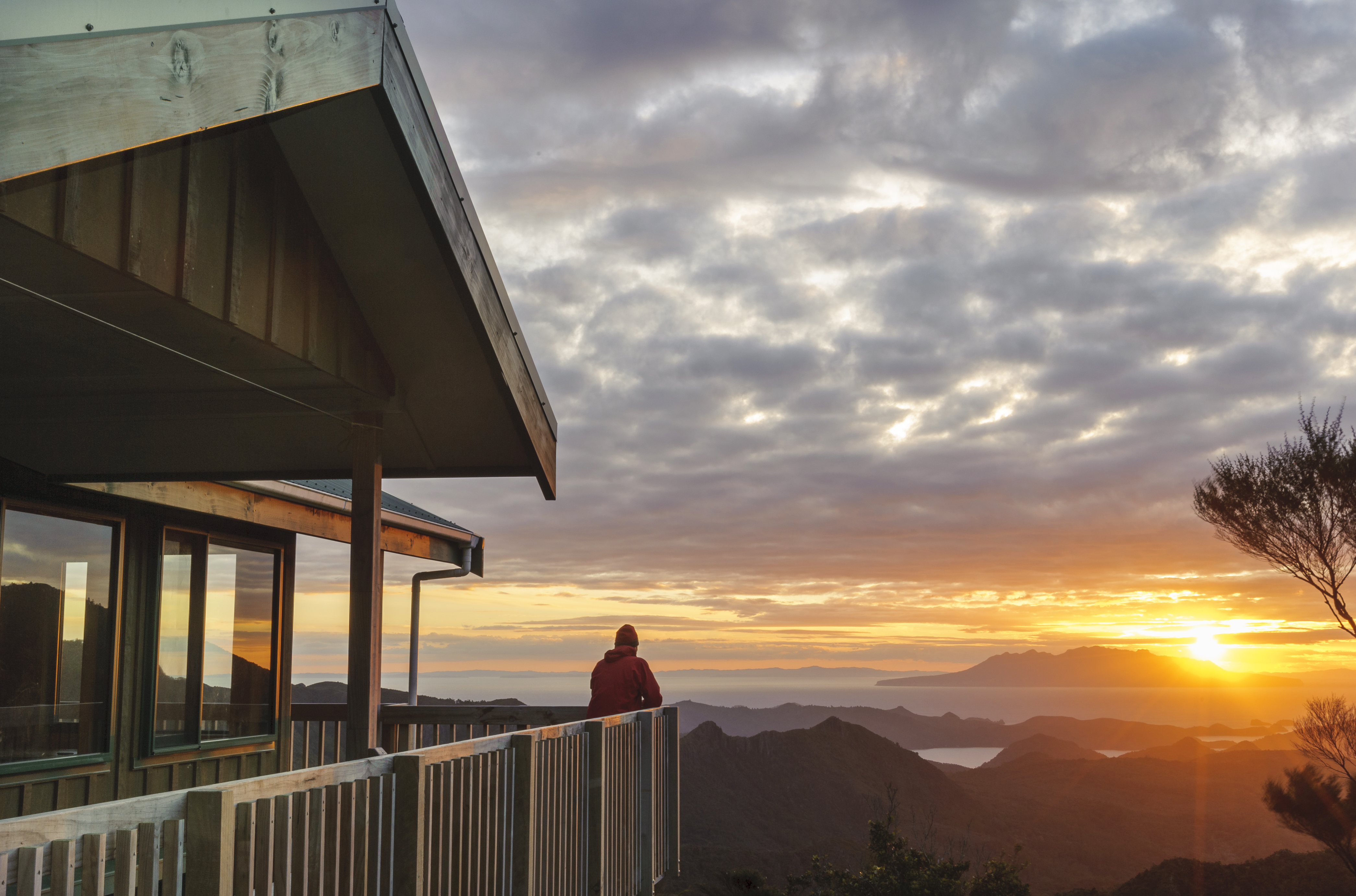 Chris Maclean watches sunset over Little Barrier Island from Mt Heale Hut, Great Barrier Island, Auckland. Photo / Shaun Barnett
