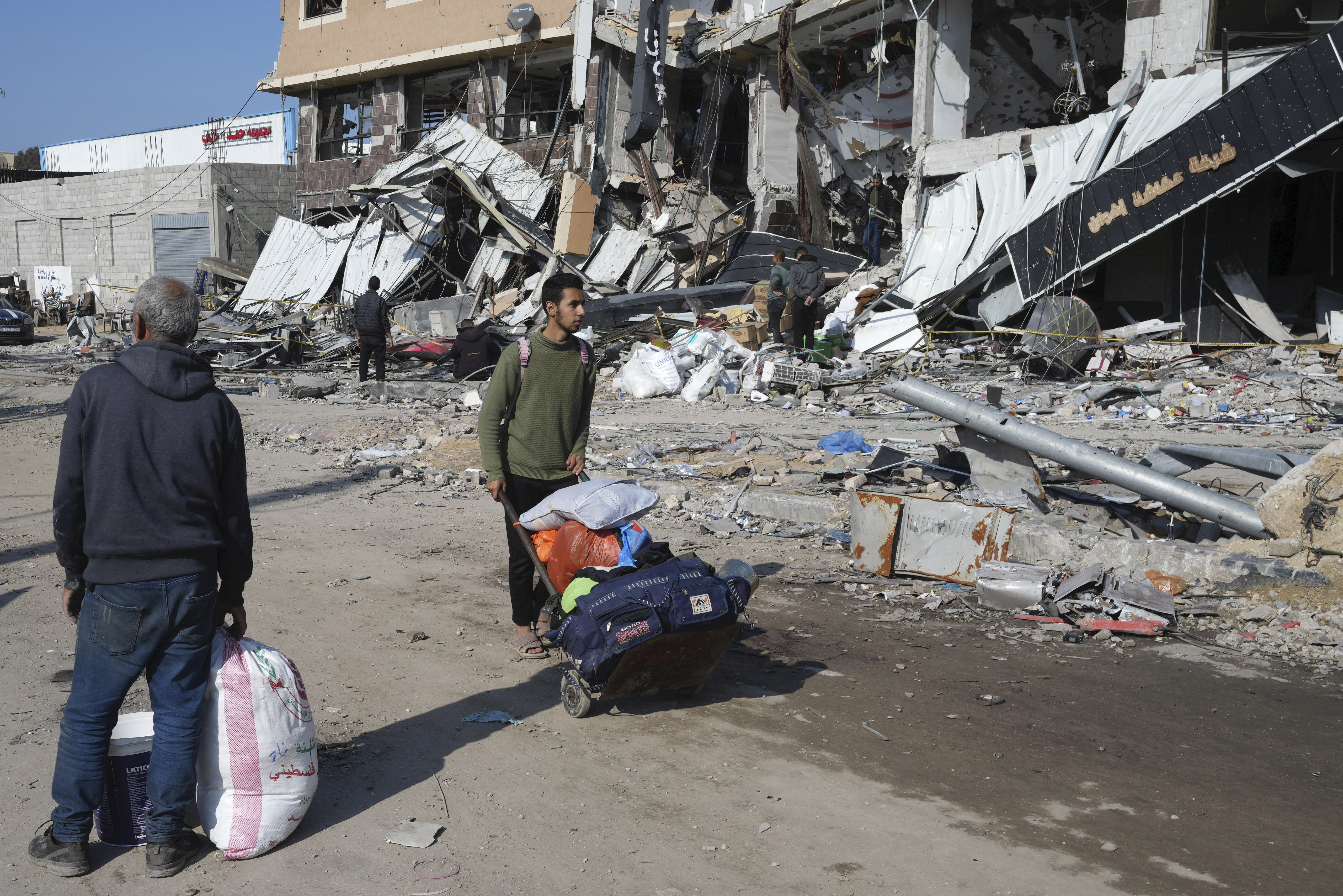 Palestinians walk through destruction by the Israeli bombardment in the Nusseirat refugee camp in Gaza Strip, Tuesday, Jan. 16, 2024. (AP Photo/Adel Hana)