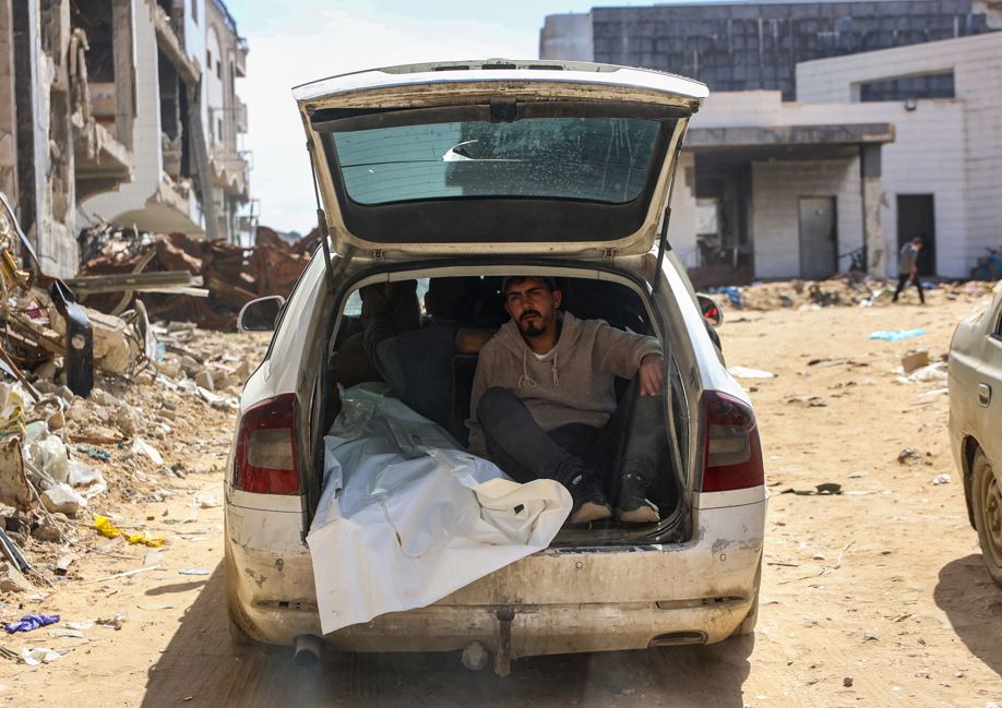 People transport a body after Palestinian civil defence workers uncovered corpses buried in the grounds of Al Shifa Hospital in Gaza City, on March 13, 2025. Photo / Omar AL-QATTAA / AFP