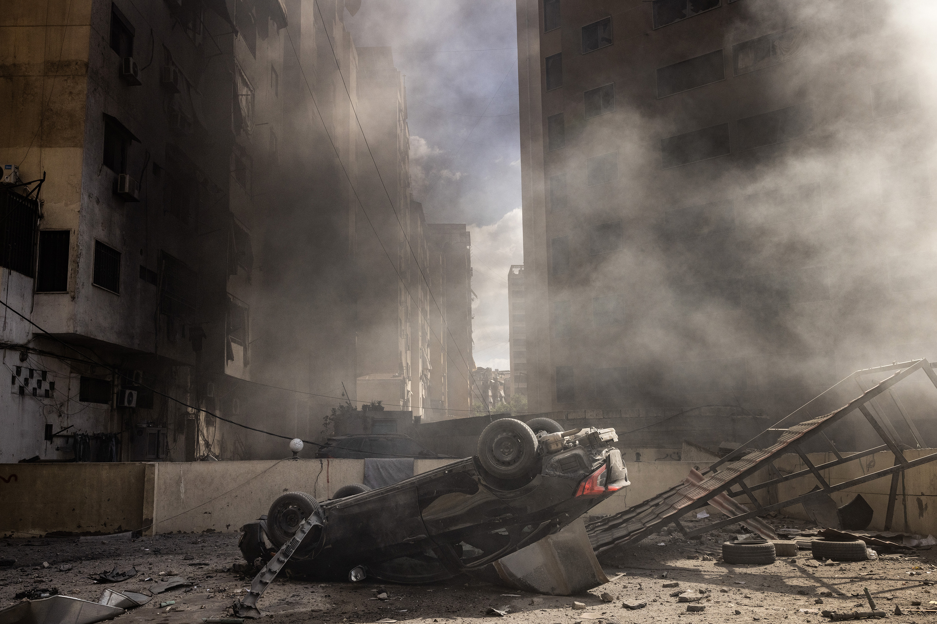 An overturned car next to the smouldering debris left after a week of Israeli airstrikes in Dahieh, Lebanon. Photo / David Guttenfelder, The New York Times