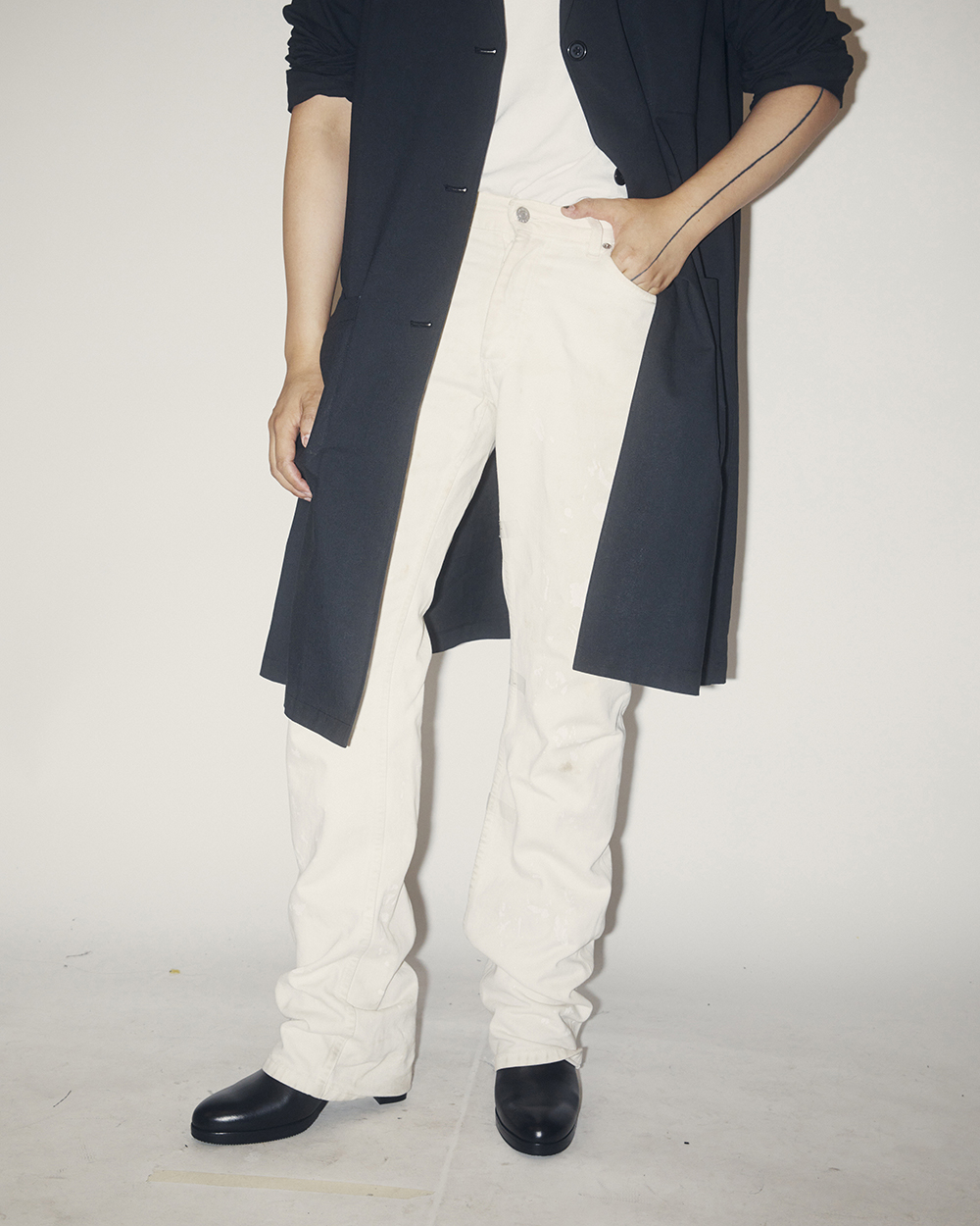 Peter Do, wearing his white vintage Helmut Lang jeans, at his studio in New York. Do has a tattoo that runs up one arm, finger to neck, like a seam. Photo / Erik Tanner, The New York Times