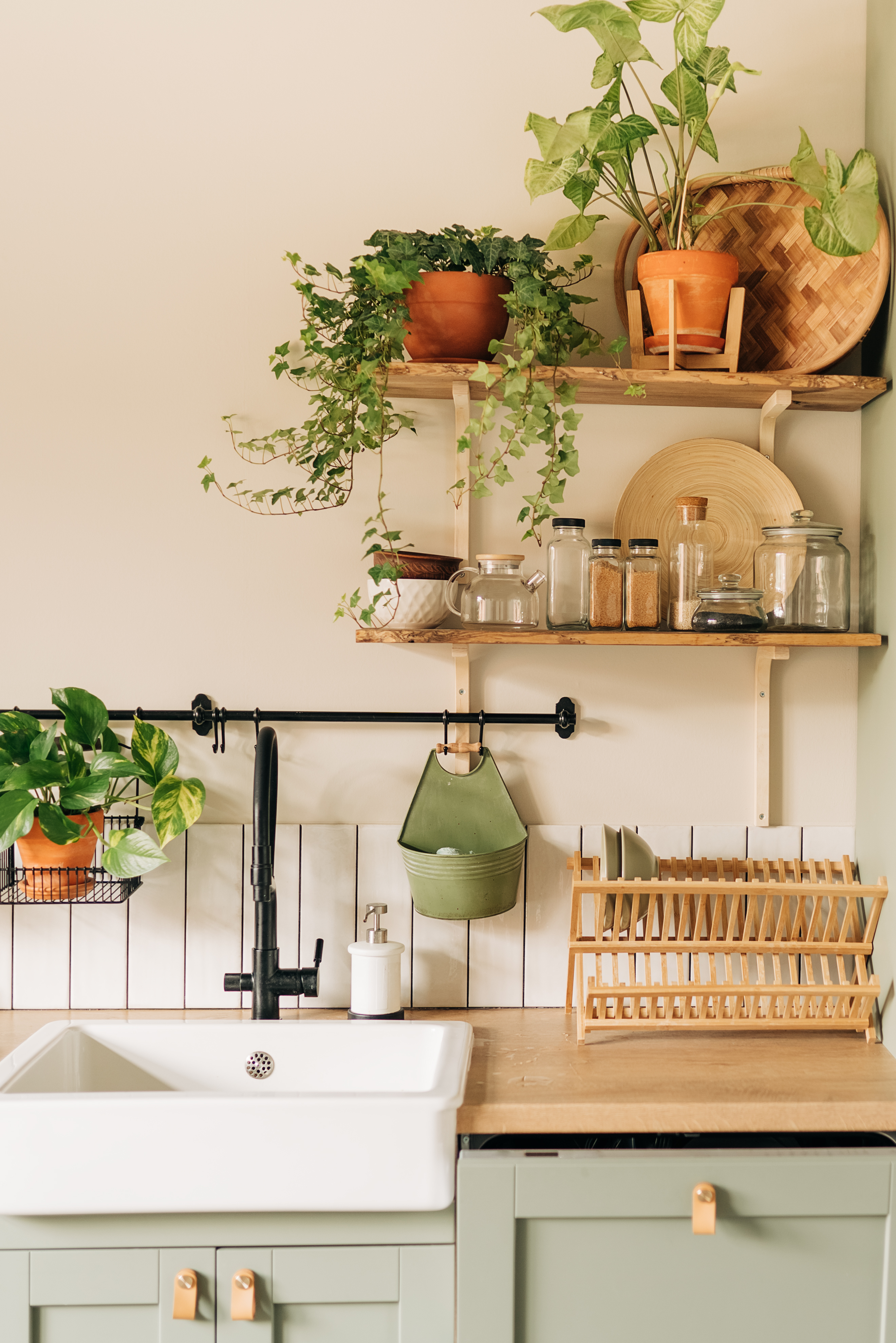 Dusty-hued cabinets and a collection of plants lend a difference to this Scandi-style kitchen. Photo / Getty Images