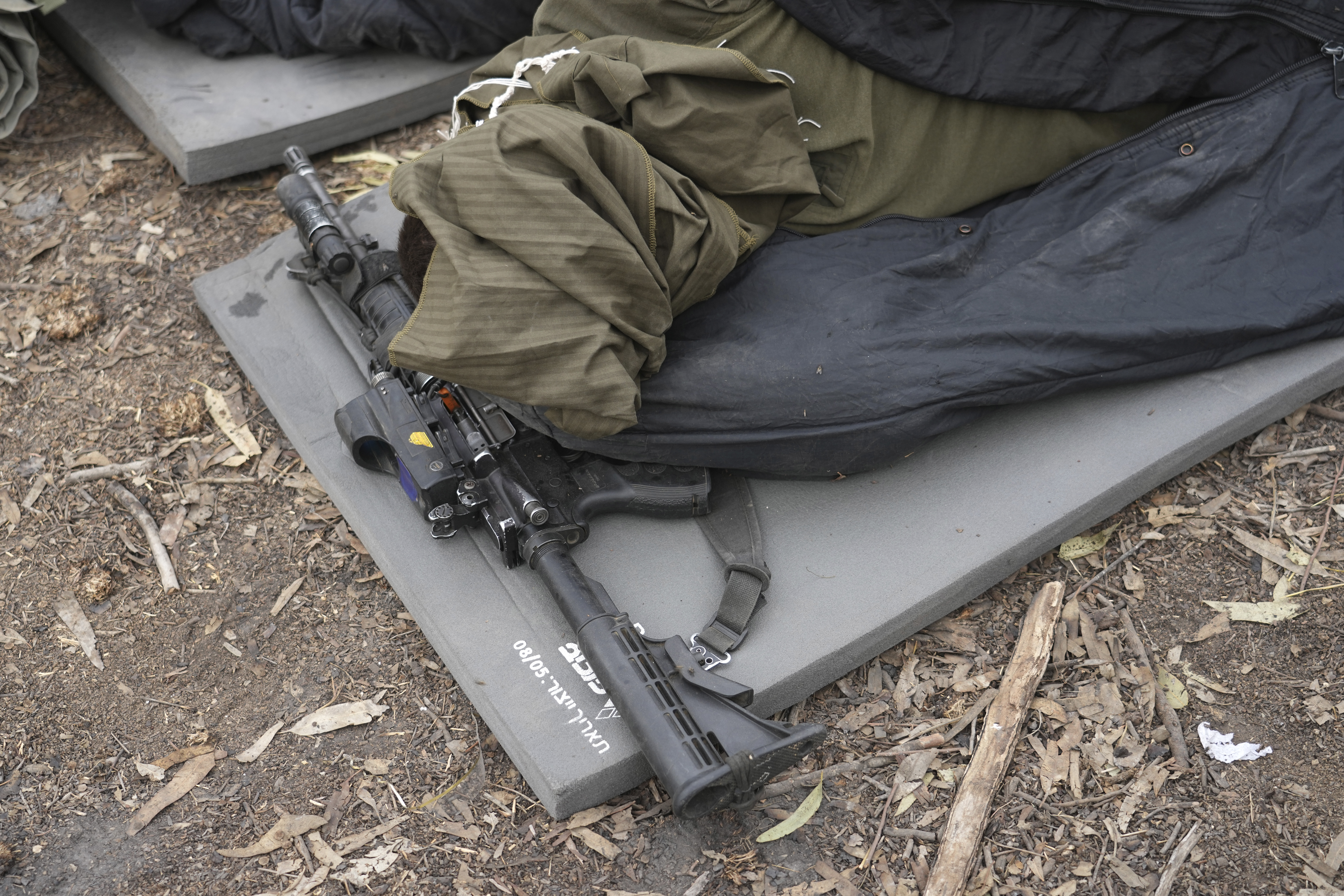 An Israeli soldier rests with his head covered and weapon close near the Israel-Gaza border in southern Israel. Photo / AP