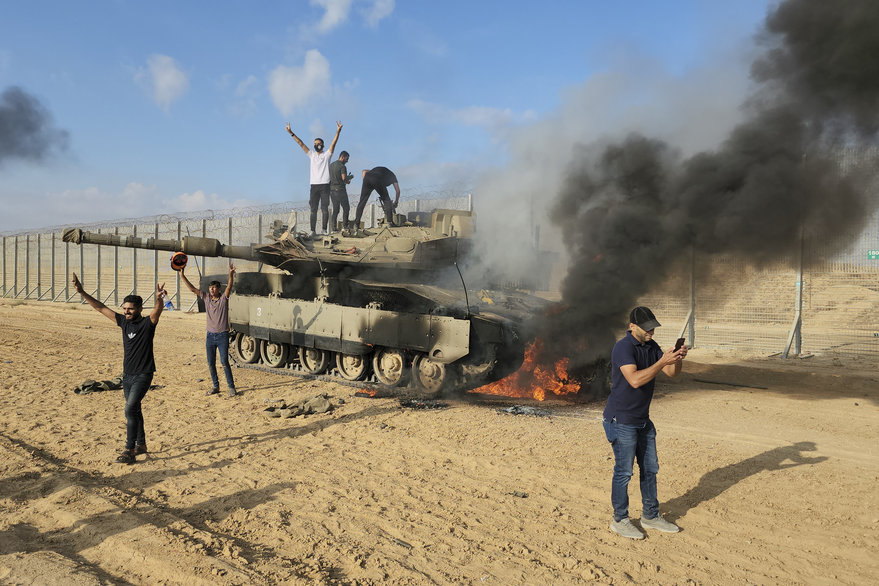 Palestinians celebrate by a destroyed Israeli tank at the Gaza Strip fence east of Khan Younis. Photo / AP