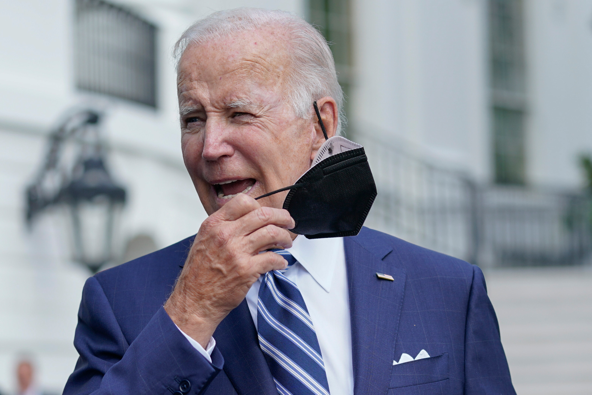 President Joe Biden removes his face mask as he walks to speak to members of the media. Photo / AP