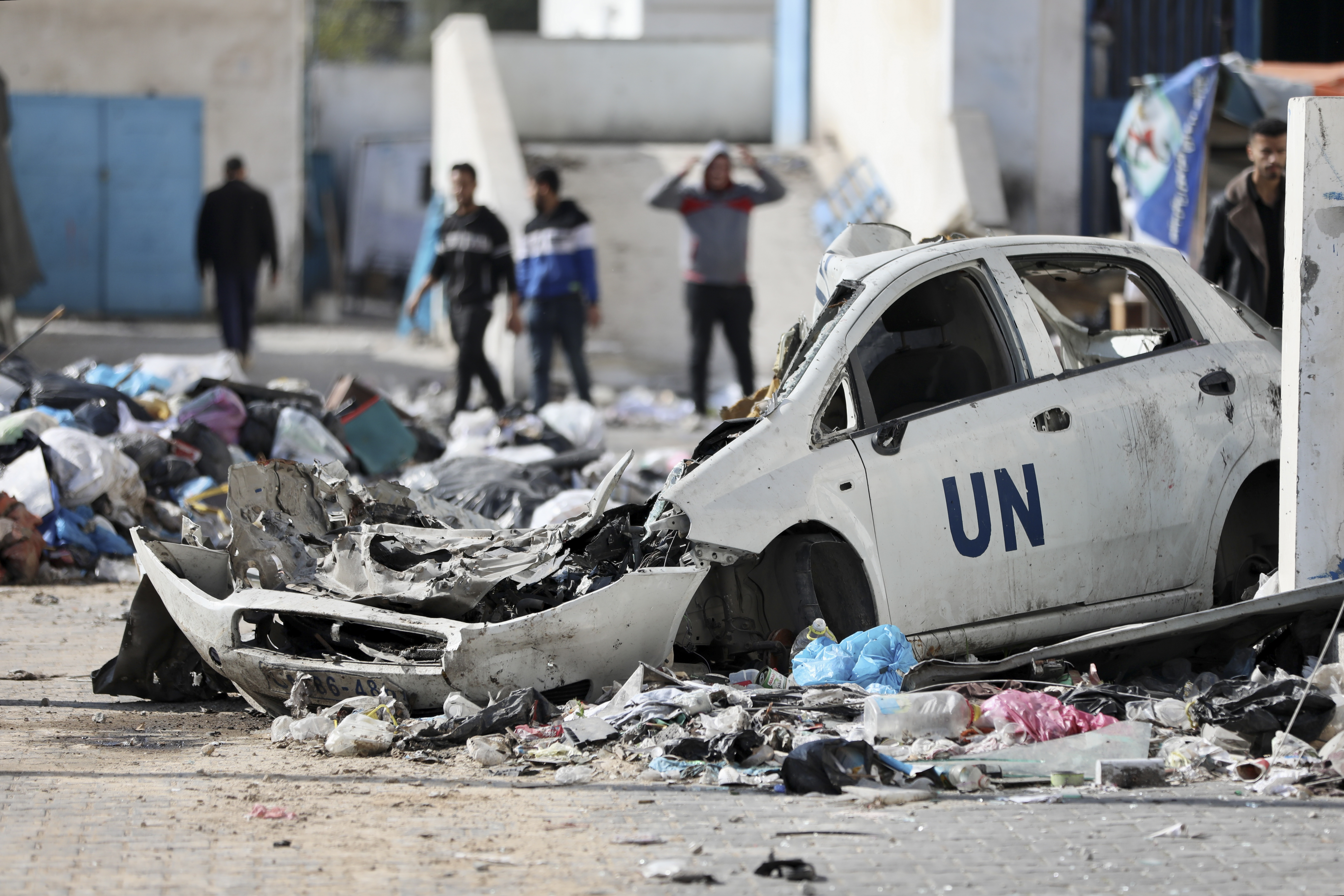 Palestinians walk through the destruction, including a crushed car which read UN, left by the Israeli air and ground offensive on the Gaza Strip. Photo / AP