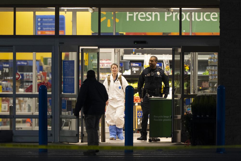 A law enforcement investigator wears a protective covering as they work the scene of a mass shooting at a Walmart. Photo / AP