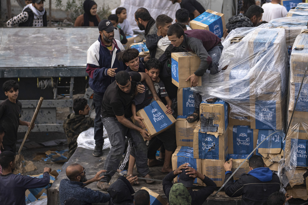 Palestinians grab supplies from a humanitarian aid truck as it crosses into the Gaza Strip in Rafah on December 17. (AP Photo/Fatima Shbair)